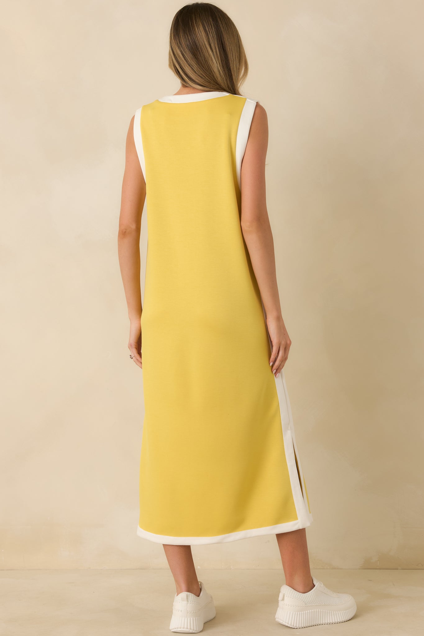 Yellow sleeveless maxi dress displaying the straight silhouette from the rear with contrast trim along the edges and smooth knit finish.