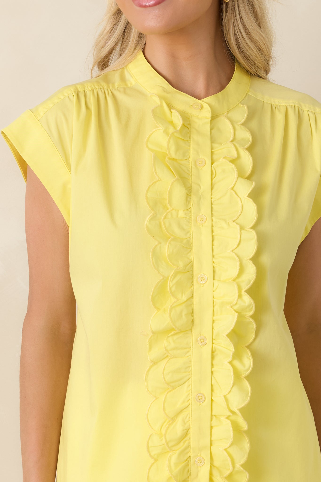 Close-up of the yellow top highlighting the scalloped ruffle edging, functional buttons, and lightweight cotton blend fabric texture.