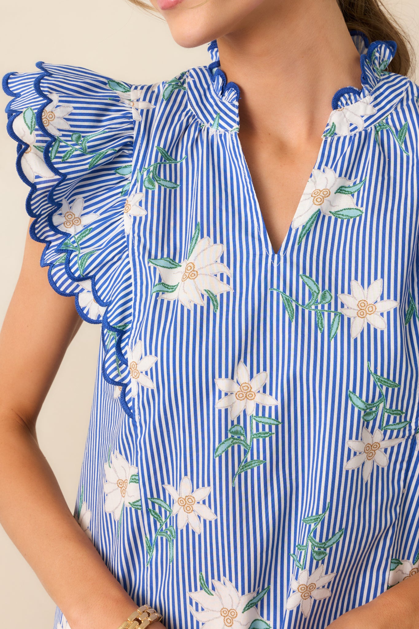 Zoomed-in on the scalloped hem of the flutter sleeves, highlighting the delicate finishing touches that make this blue top unique.