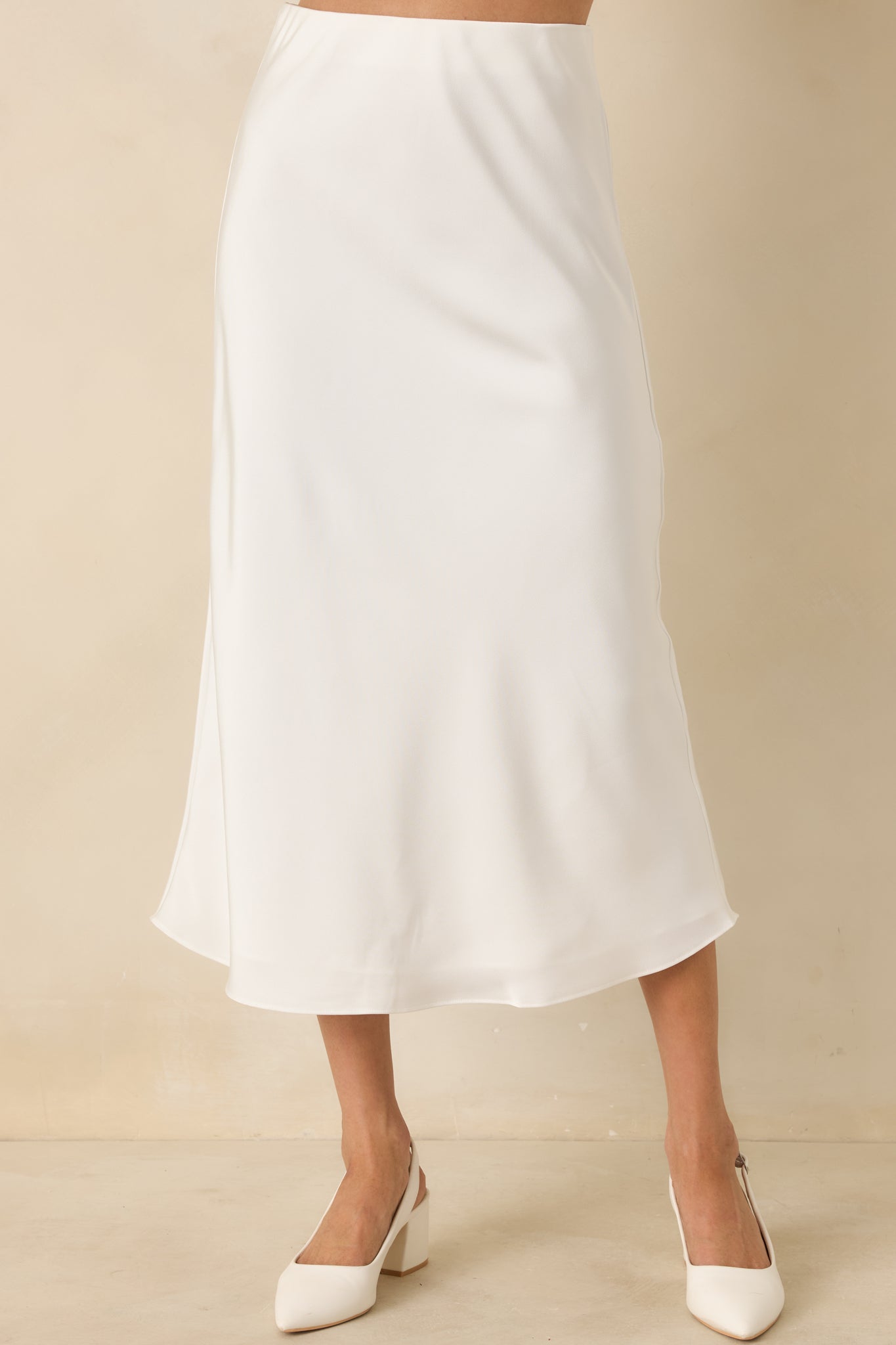 Zoomed-in look at the hemline of the white midi skirt, emphasizing the fluid drape and clean finish.