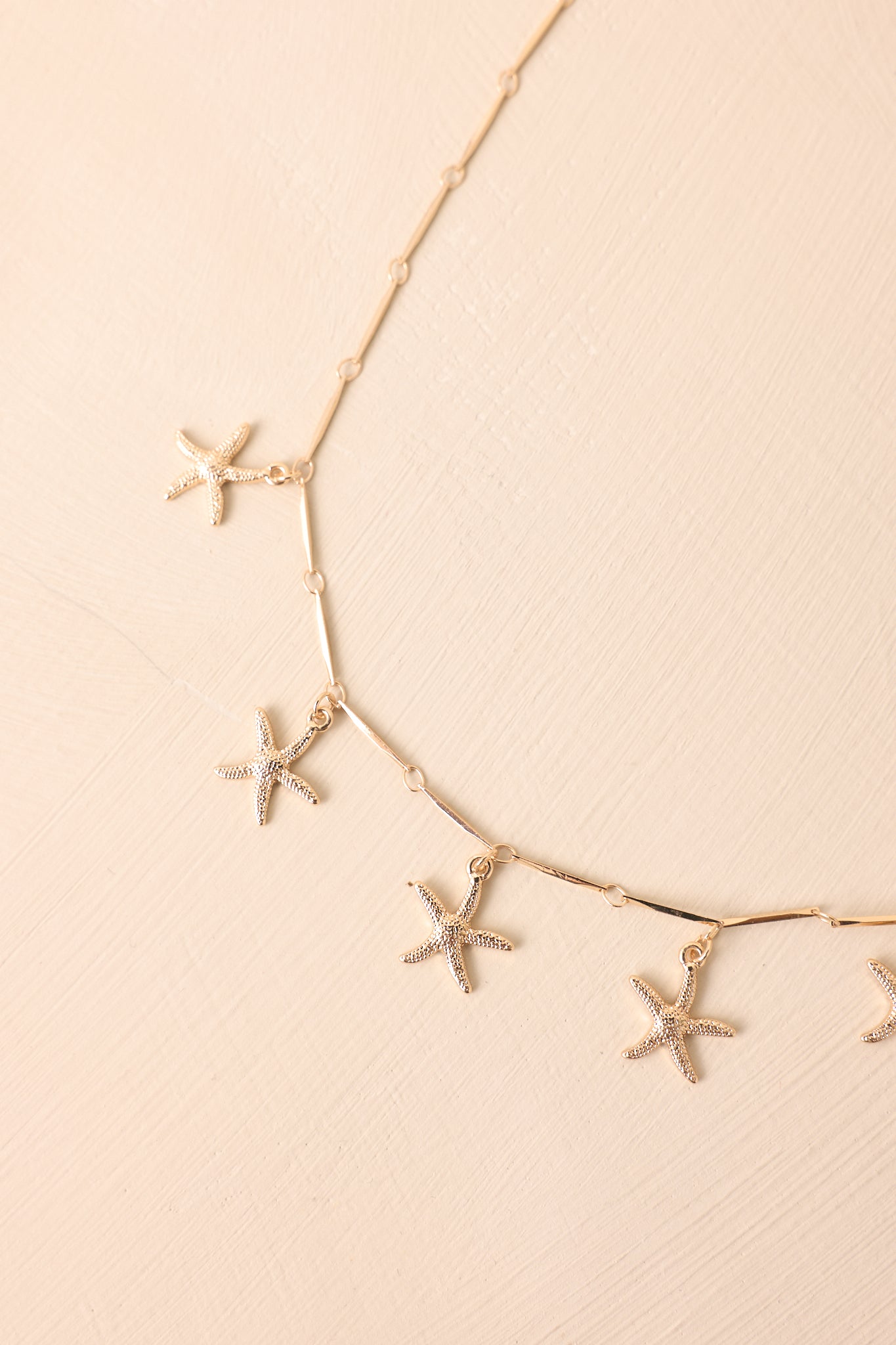 A zoomed-in shot of the textured starfish charms evenly spaced along the thin chain link.