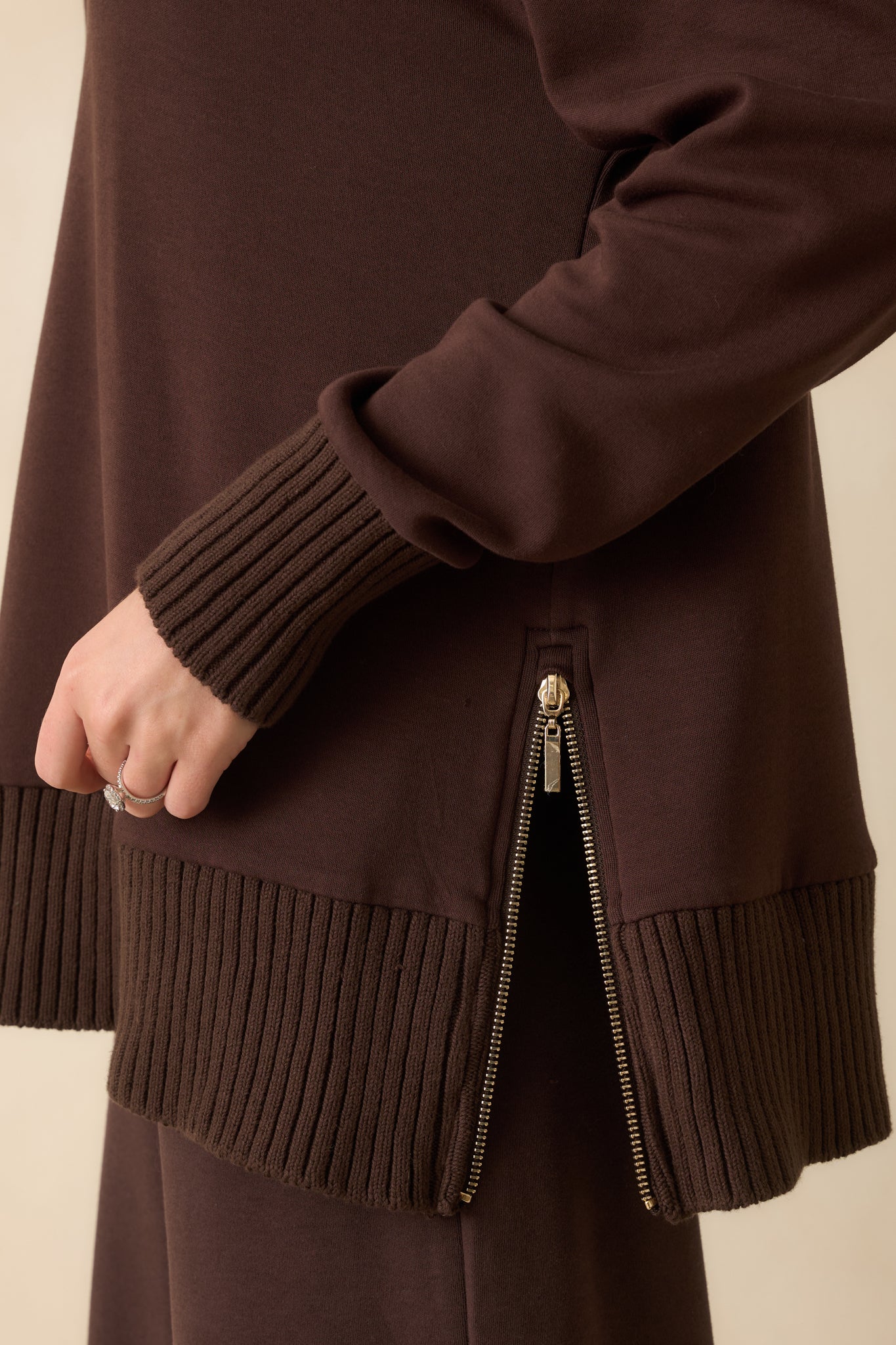 A zoomed-in shot of the dark brown sweater capturing the side zipper closure.