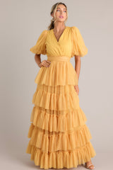 Full body view of this yellow dress features a v-neckline, puff sleeves, elastic stretch around the waist, a removable self-tie at the waist, and a tiered flowy skirt.