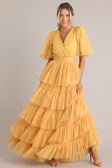 This yellow dress features a v-neckline, puff sleeves, elastic stretch around the waist, a removable self-tie at the waist, and a tiered flowy skirt.