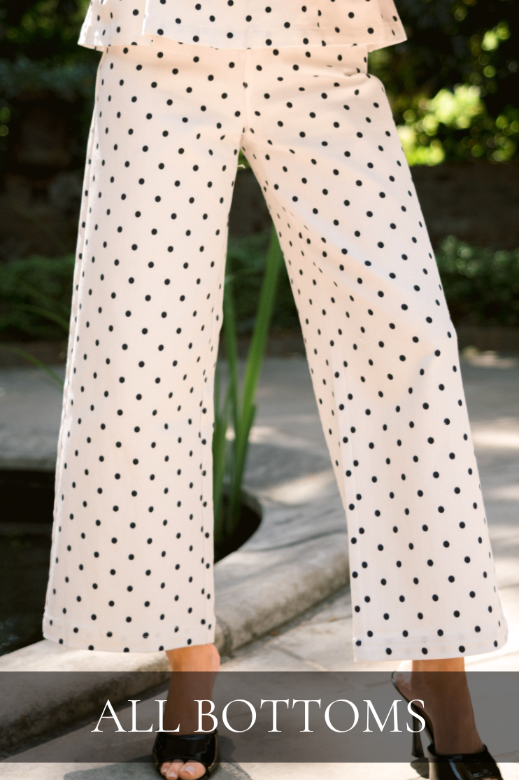 White wide-leg pants with black polka dots worn outdoors. Pants are featured in the All Bottoms Collection.
