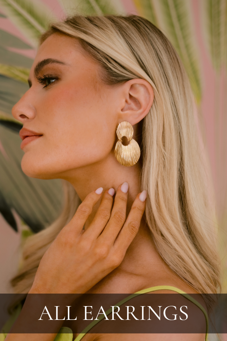 Model wearing gold drop earrings with layered oval discs and intricate ridged texture, creating a polished and modern statement look. Earrings featured in All Earrings shop.