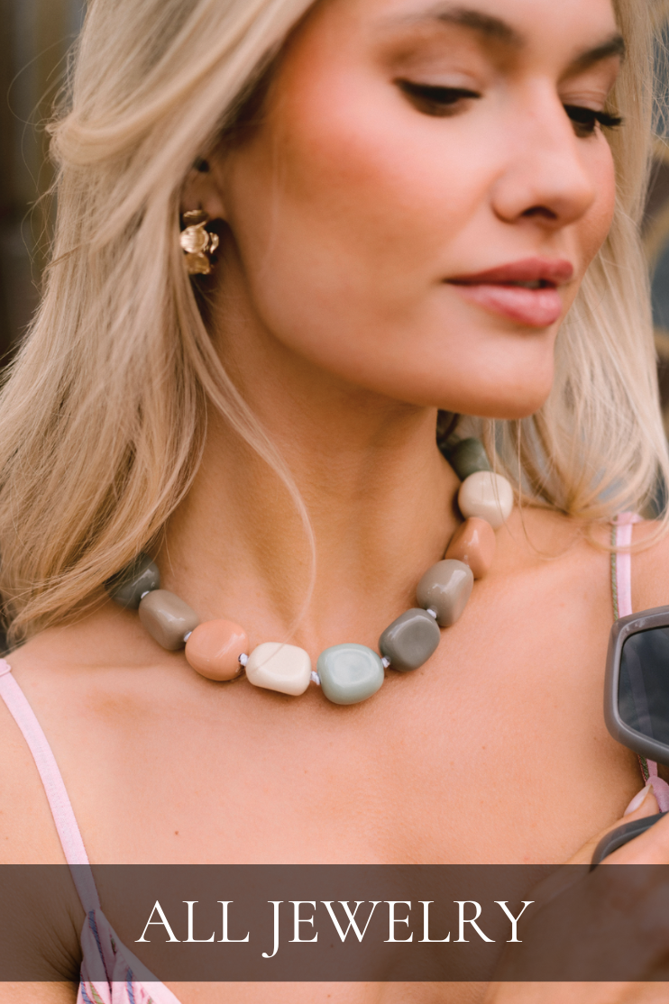 Model wearing a chunky beaded necklace with neutral tones. Necklace is featured in All Jewelry collection.