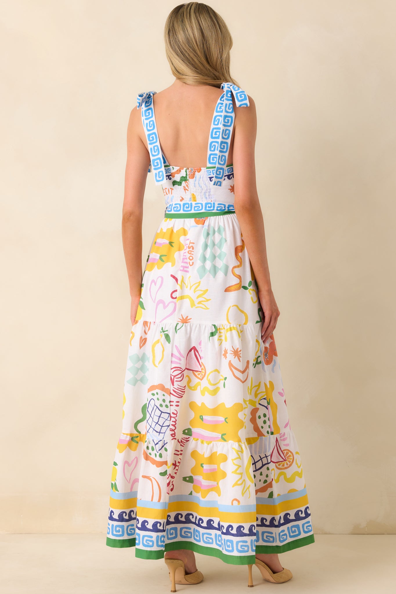A view from behind displaying the smocked panel, hidden zipper, and full length of the multicolor print flowing down the maxi silhouette.