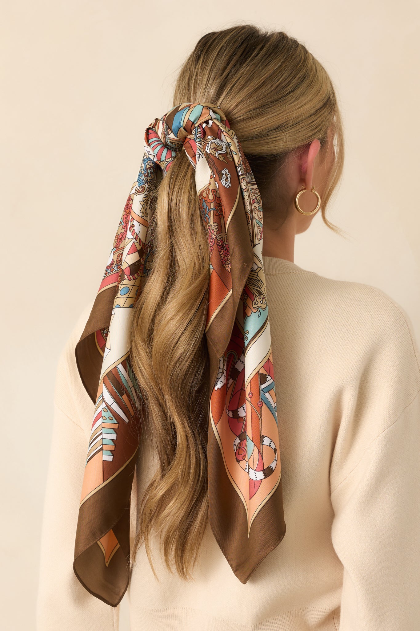 A view from behind showing the scarf styled on the head, with multiple motifs and brown-toned prints visible across the back.