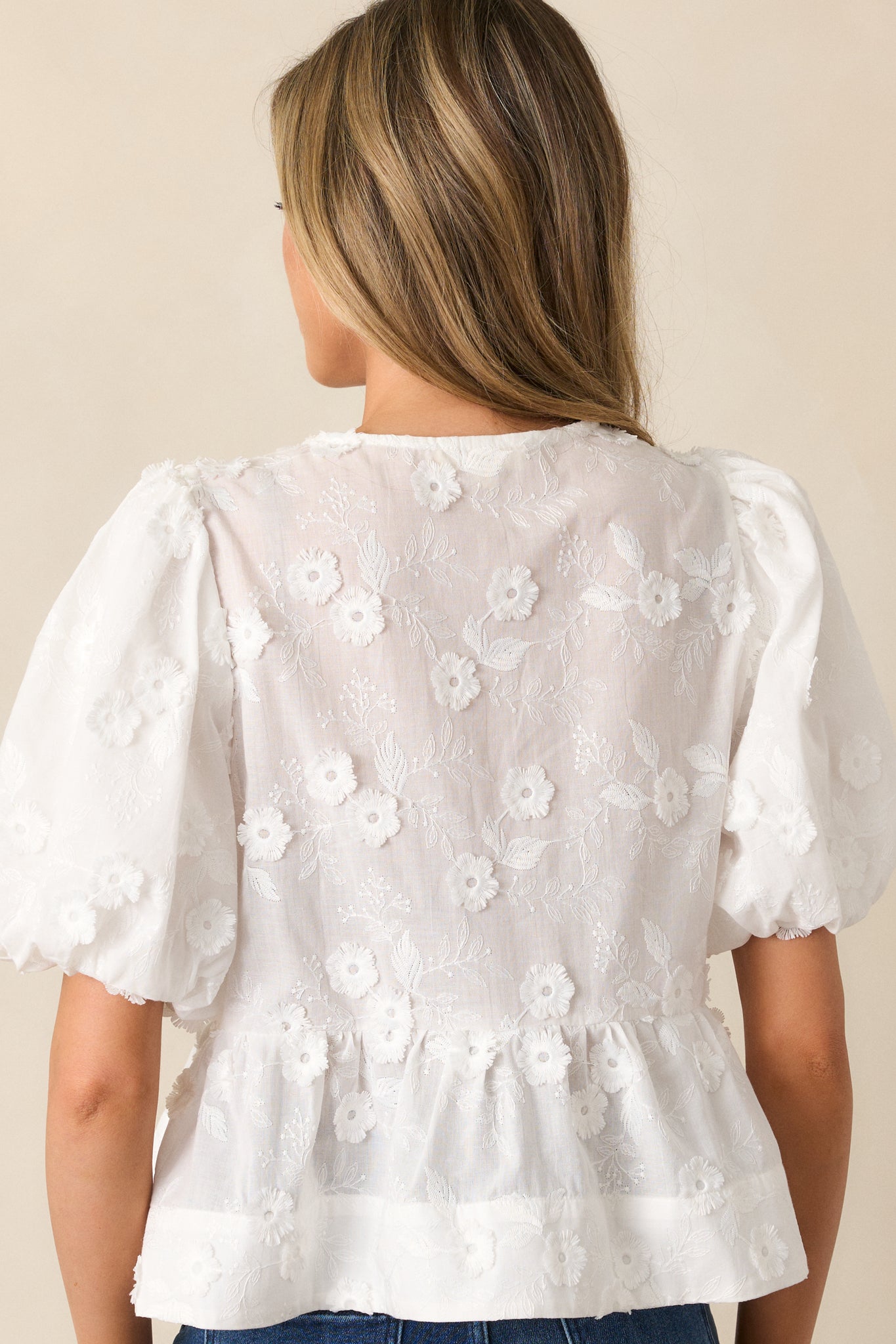 A back view of the white blouse, showing the smooth fit and clean lines, with the peplum bottom adding structure to the silhouette.