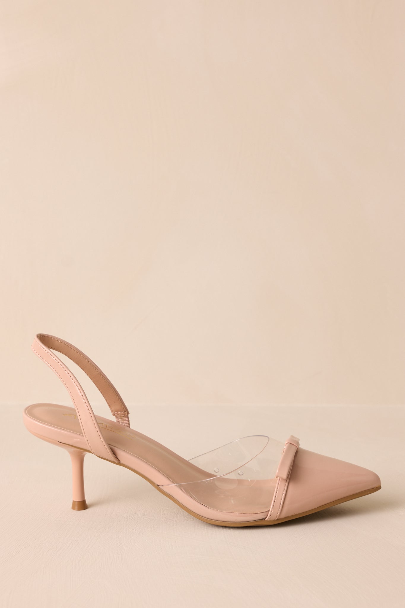 Beige background view featuring the pointed toe, bow accents, and short heel