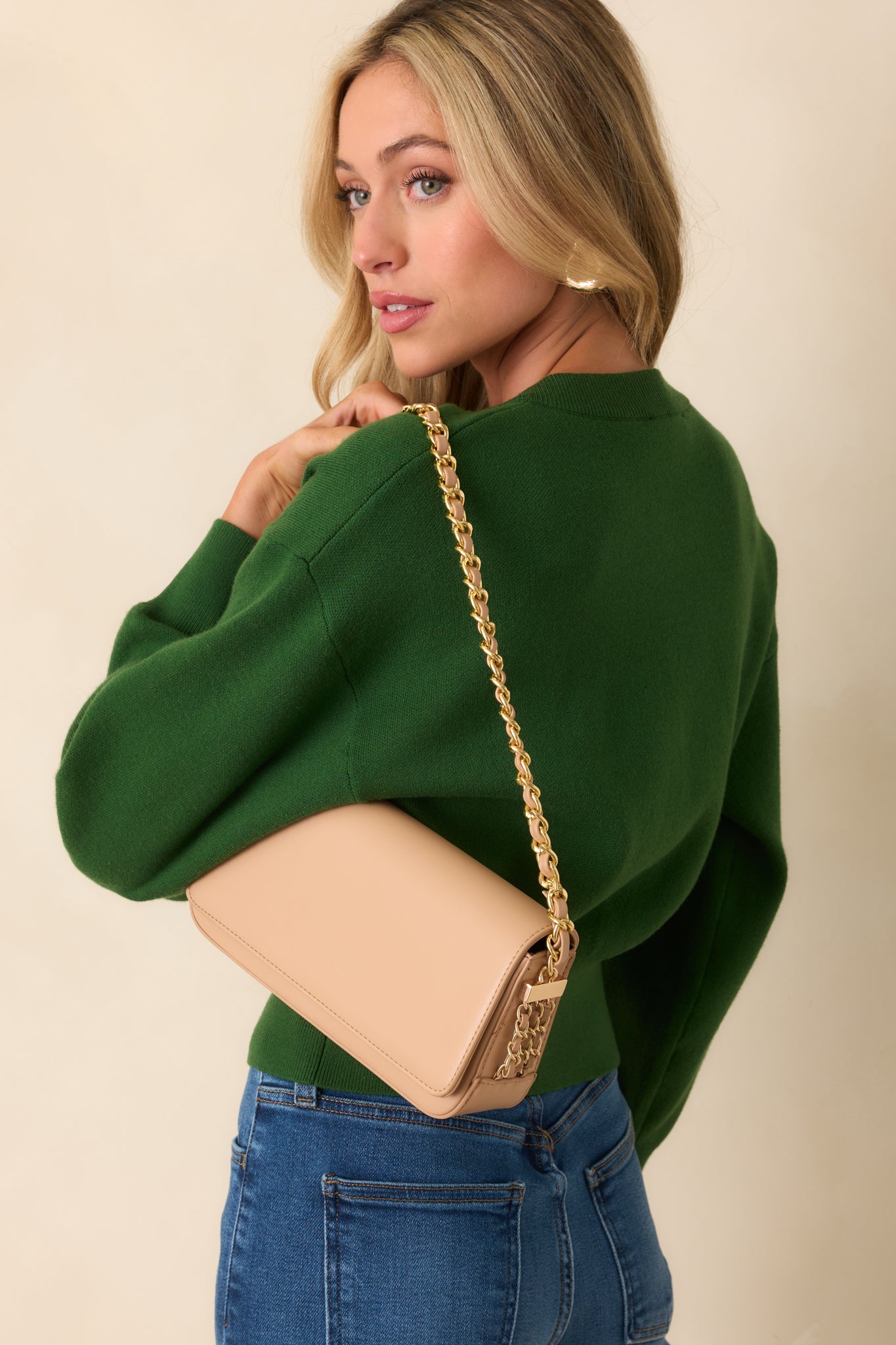 Angled full body shot highlighting the side decorative chain details and compact, curved shape of the baguette-style bag.