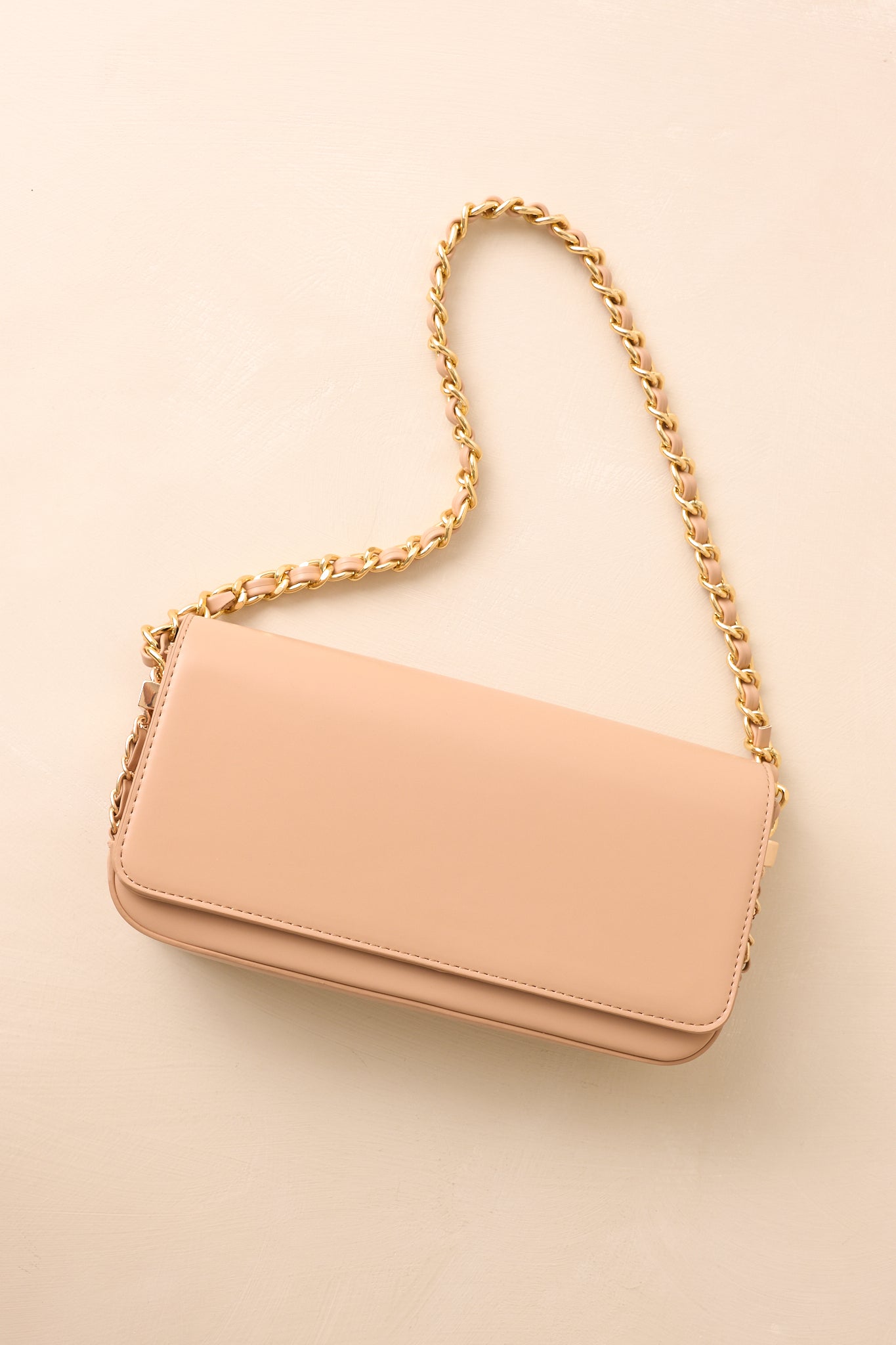 Beige handbag highlighting side decorative chain detail and structured baguette shape.