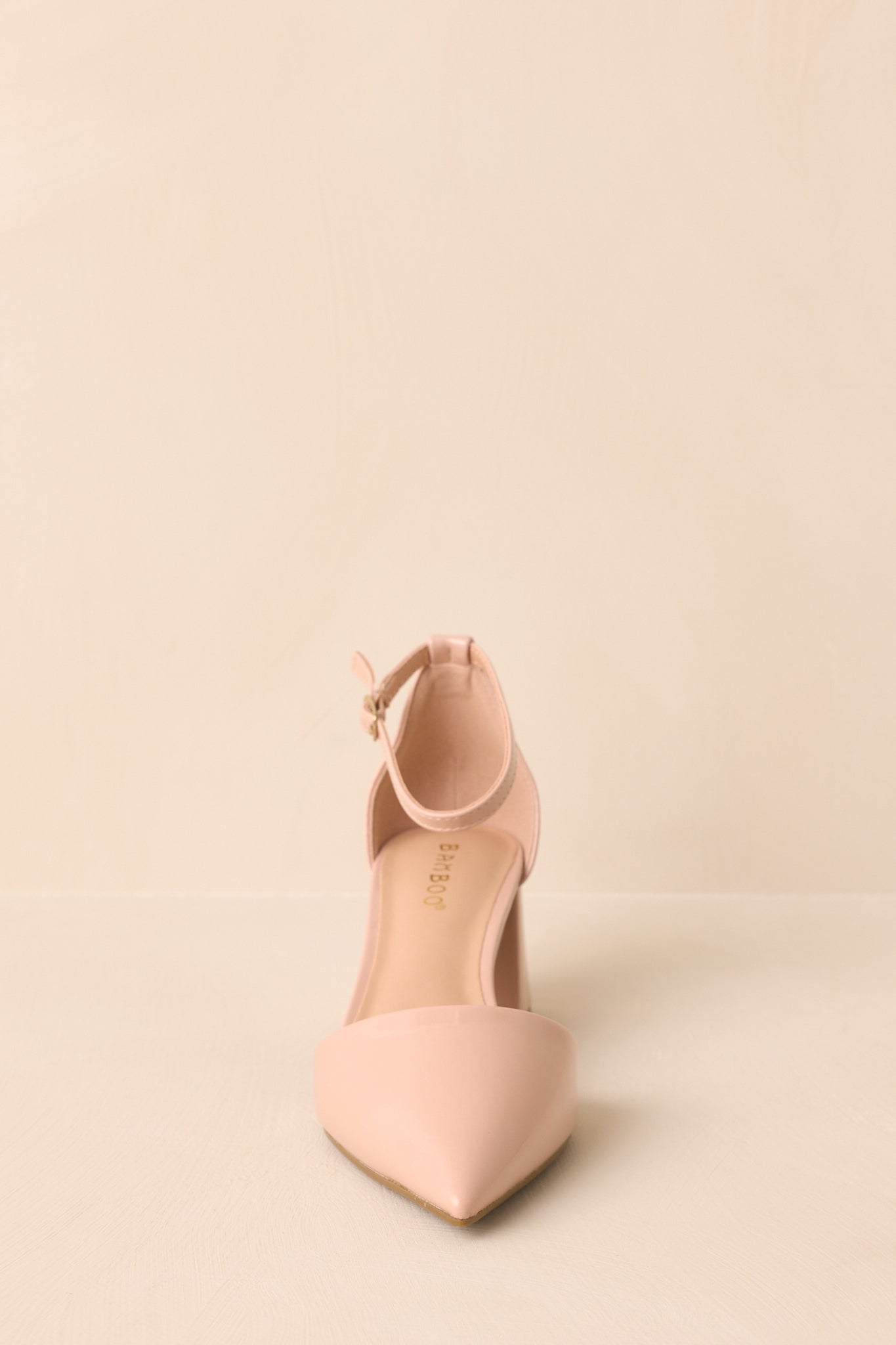 Front-facing view of both heels against a beige background, focusing on toe alignment and structure.