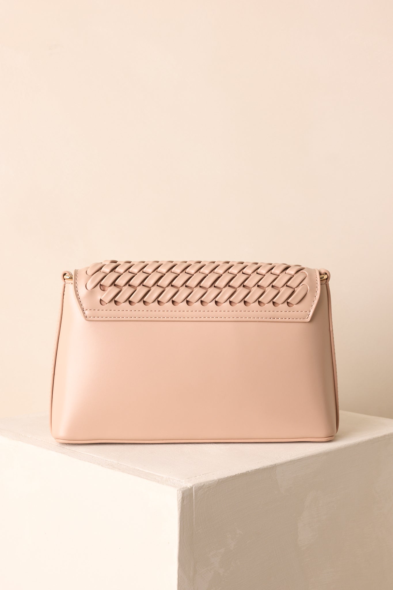 Rear view of beige handbag with woven pattern and smooth back panel.