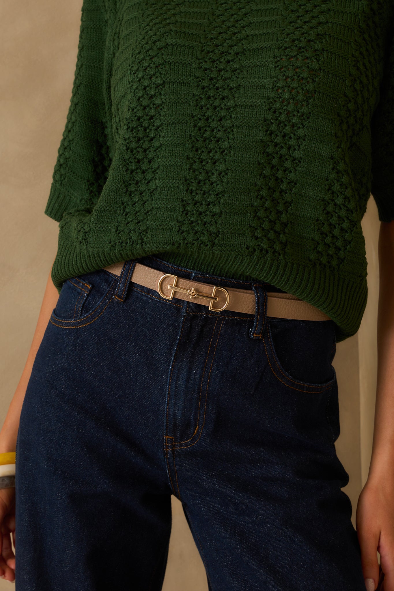 Front-facing cropped image of the belt highlighting the contrast between the gold hardware and the soft tan material.