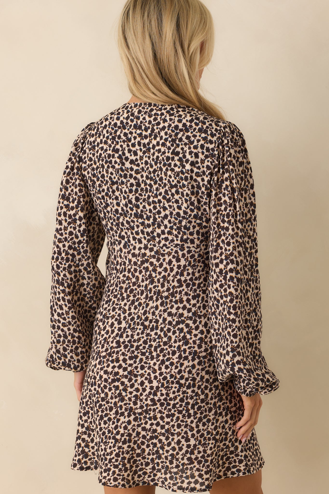 Rear view of mini dress with abstract black floral print, long puff sleeves, and hidden side zipper.