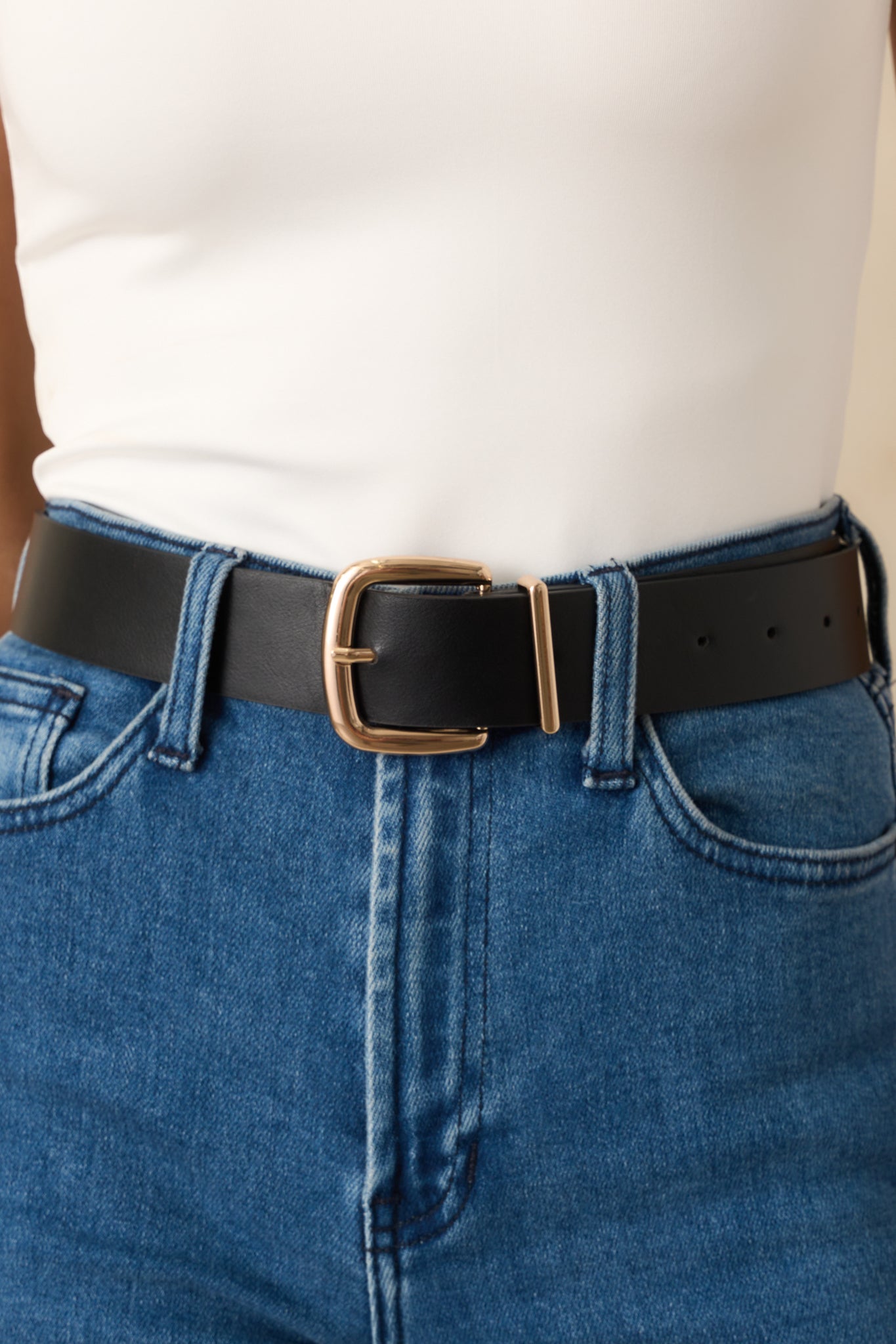 Cropped view of the black belt showing the gold-tone square buckle and stitched faux leather material.