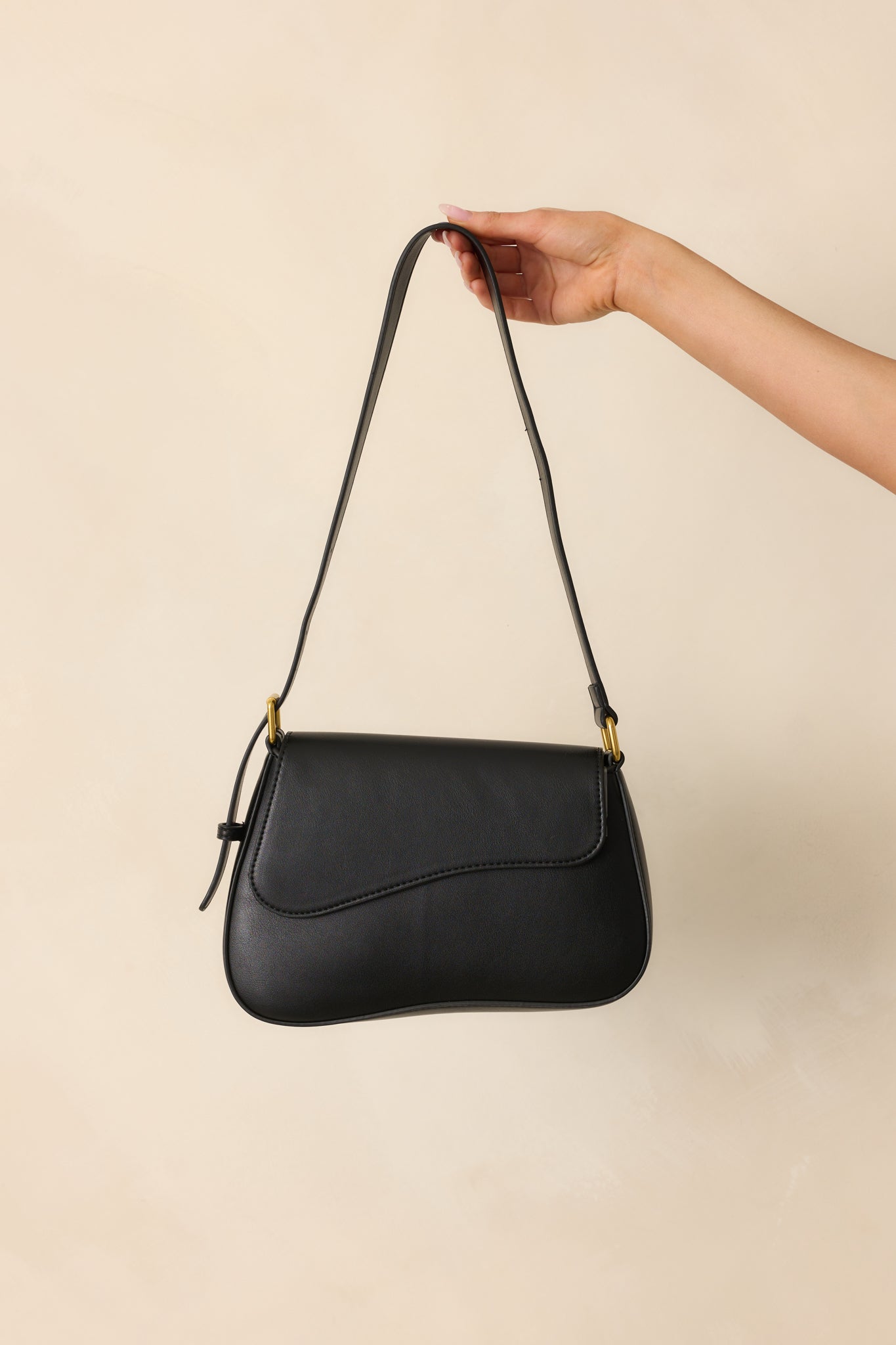 Cropped view focused on the flap-front closure and the smooth black faux leather with visible tonal stitching.