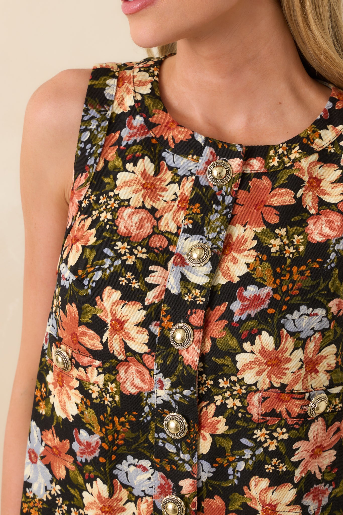 Detailed view of the embossed gold dome button against the floral black fabric.