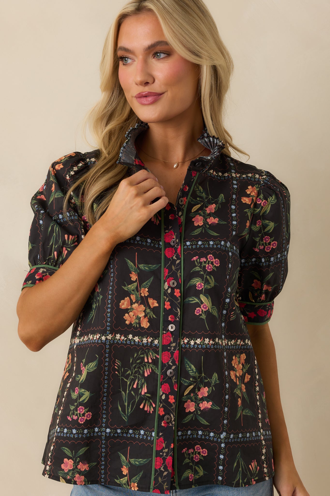 A cropped image capturing the button front and multicolor floral print details on the black top.