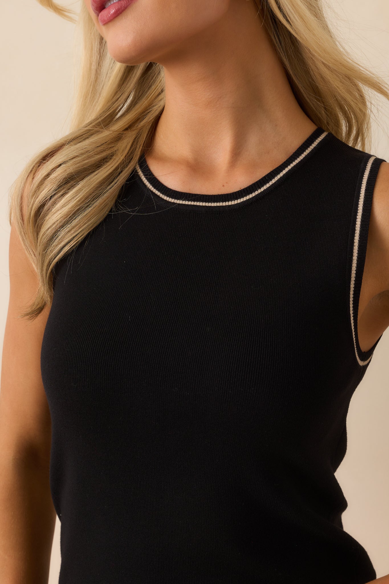 Detailed view of the ribbed knit fabric and ivory trim stitching on the neckline.