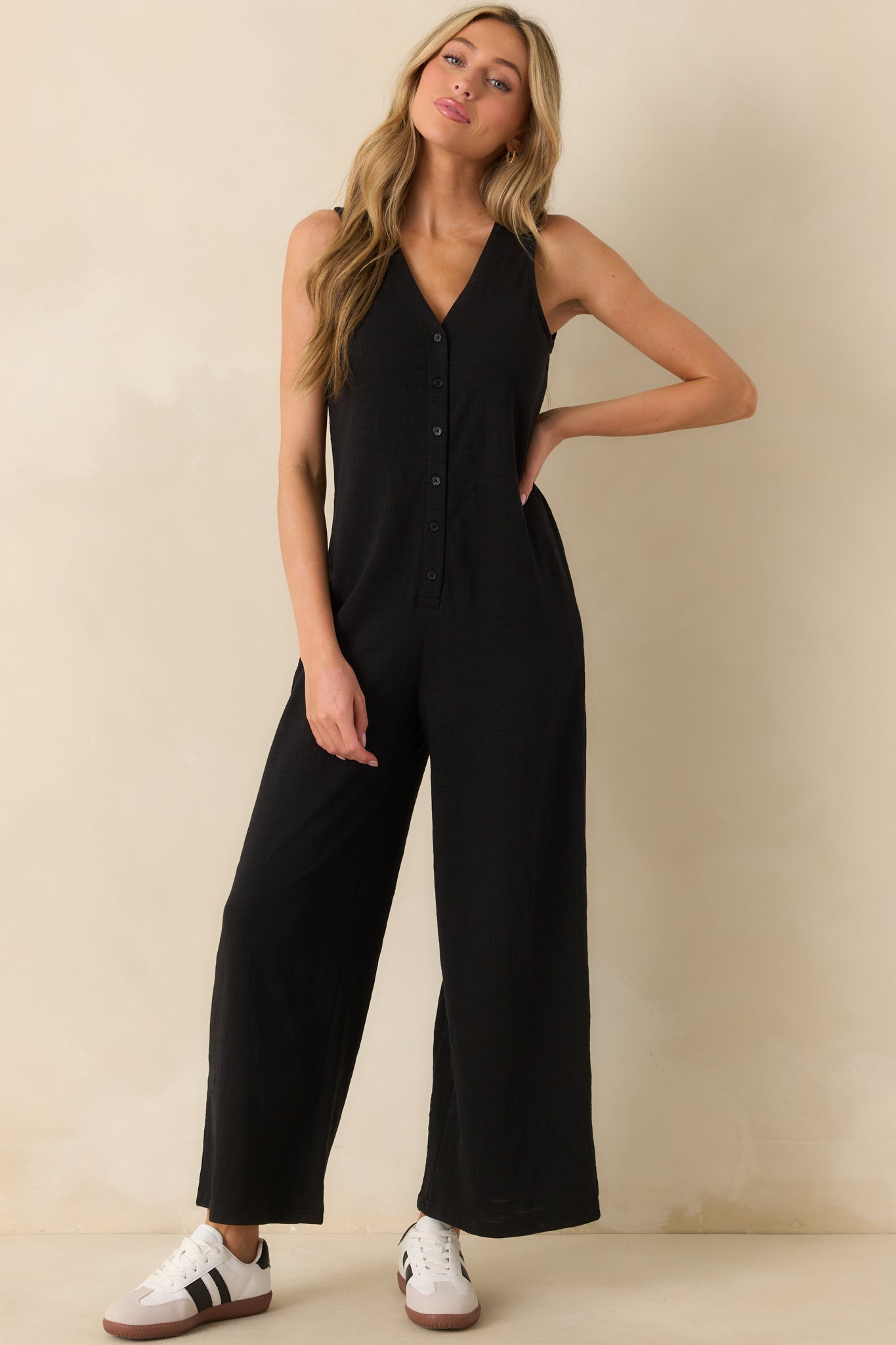 Full body front view highlighting the button front bodice of the black sleeveless jumpsuit.