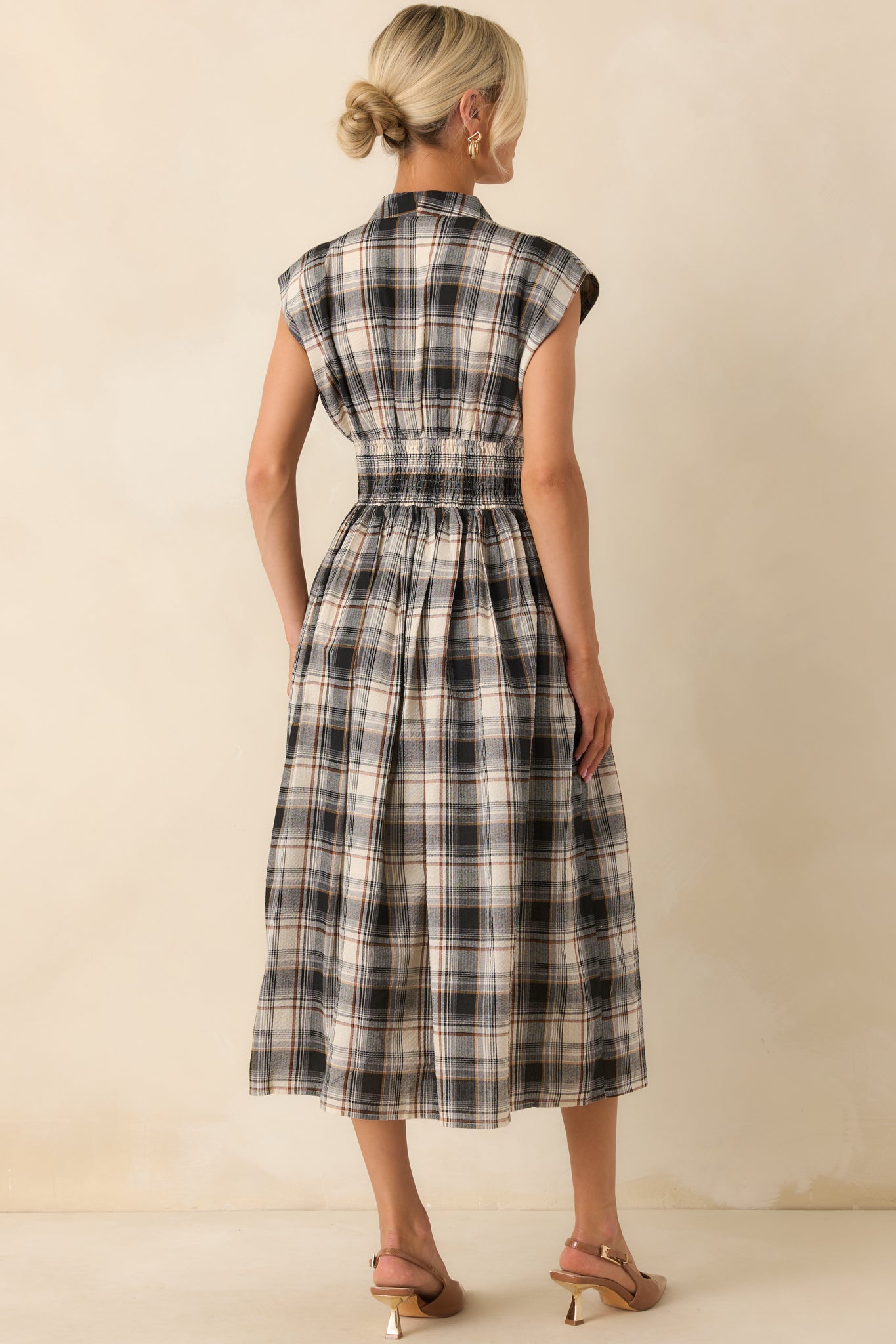 A view from behind showing the black midi dress with capped sleeves, a smocked waist, and continuous plaid pattern.
