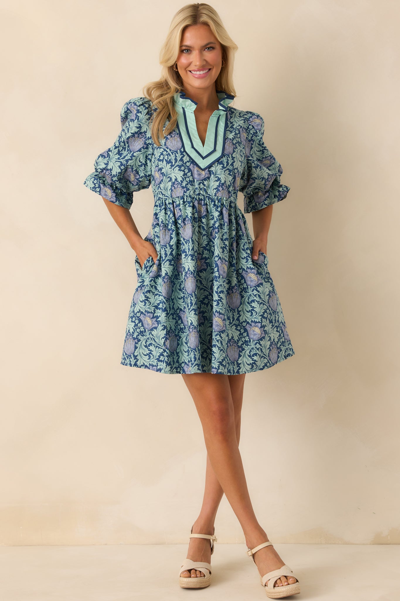 Full front-facing image of the mini dress highlighting the ruffle neckline and functional pockets.