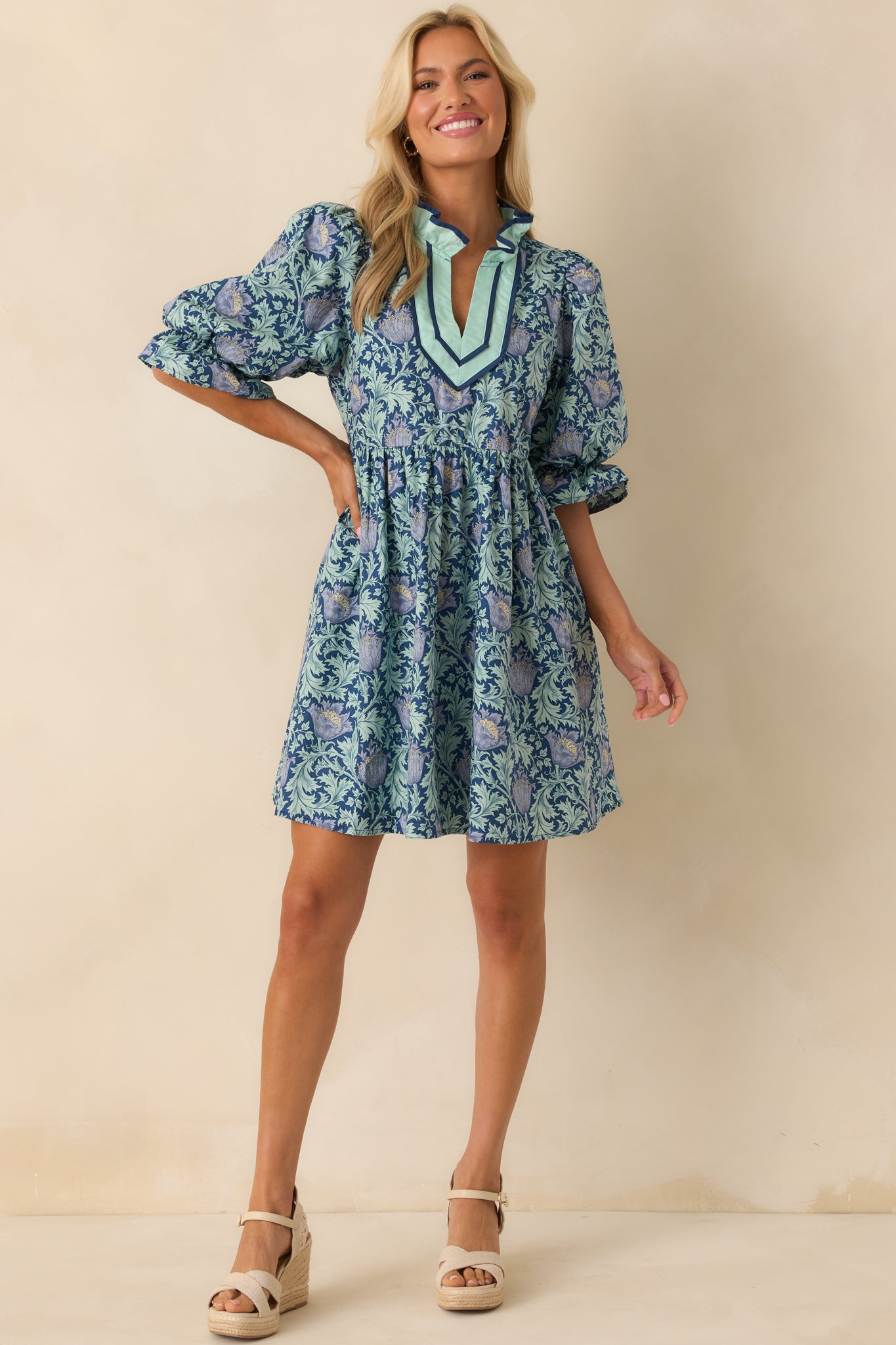 Navy mini dress with multicolor floral print, ruffle notch v-neckline, and half puff sleeves shown in a full front view.