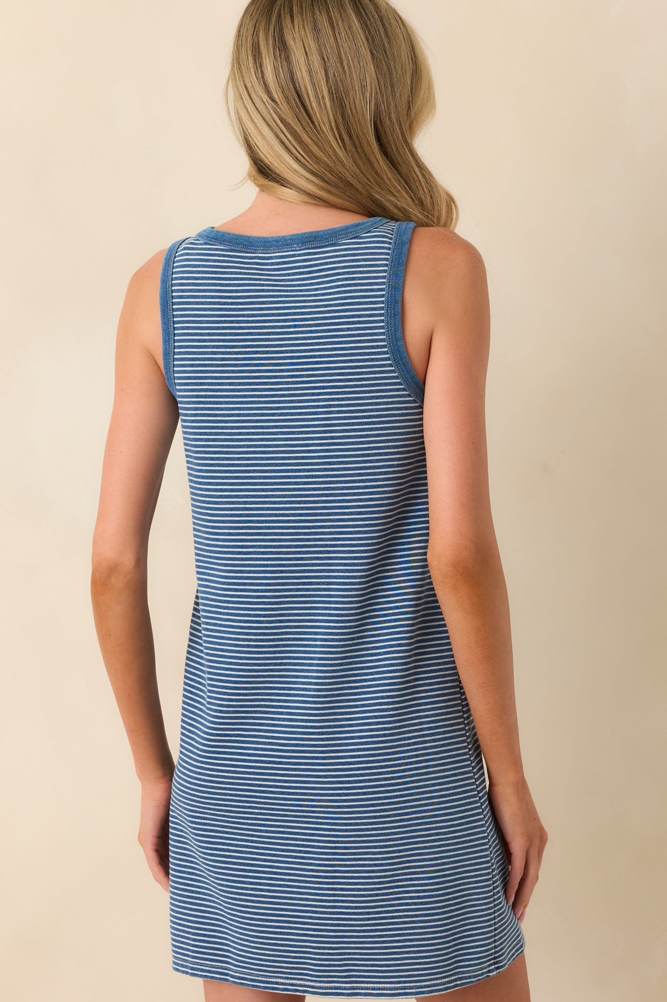 A view from behind of the mini dress showing the continuous stripe print, shift silhouette, and solid blue trim along the neckline and armholes.