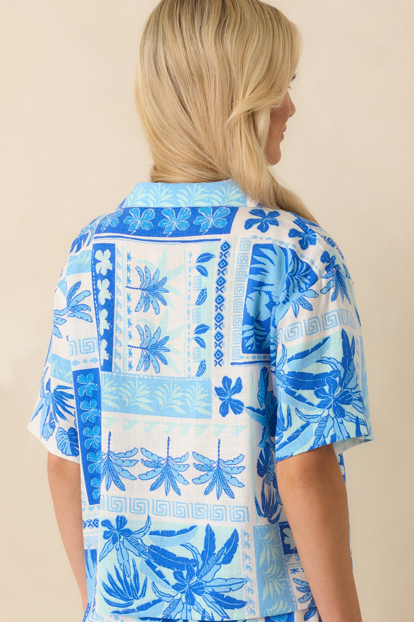 A view from behind of the top revealing the continuation of the blue tropical patchwork print and the short sleeve silhouette.