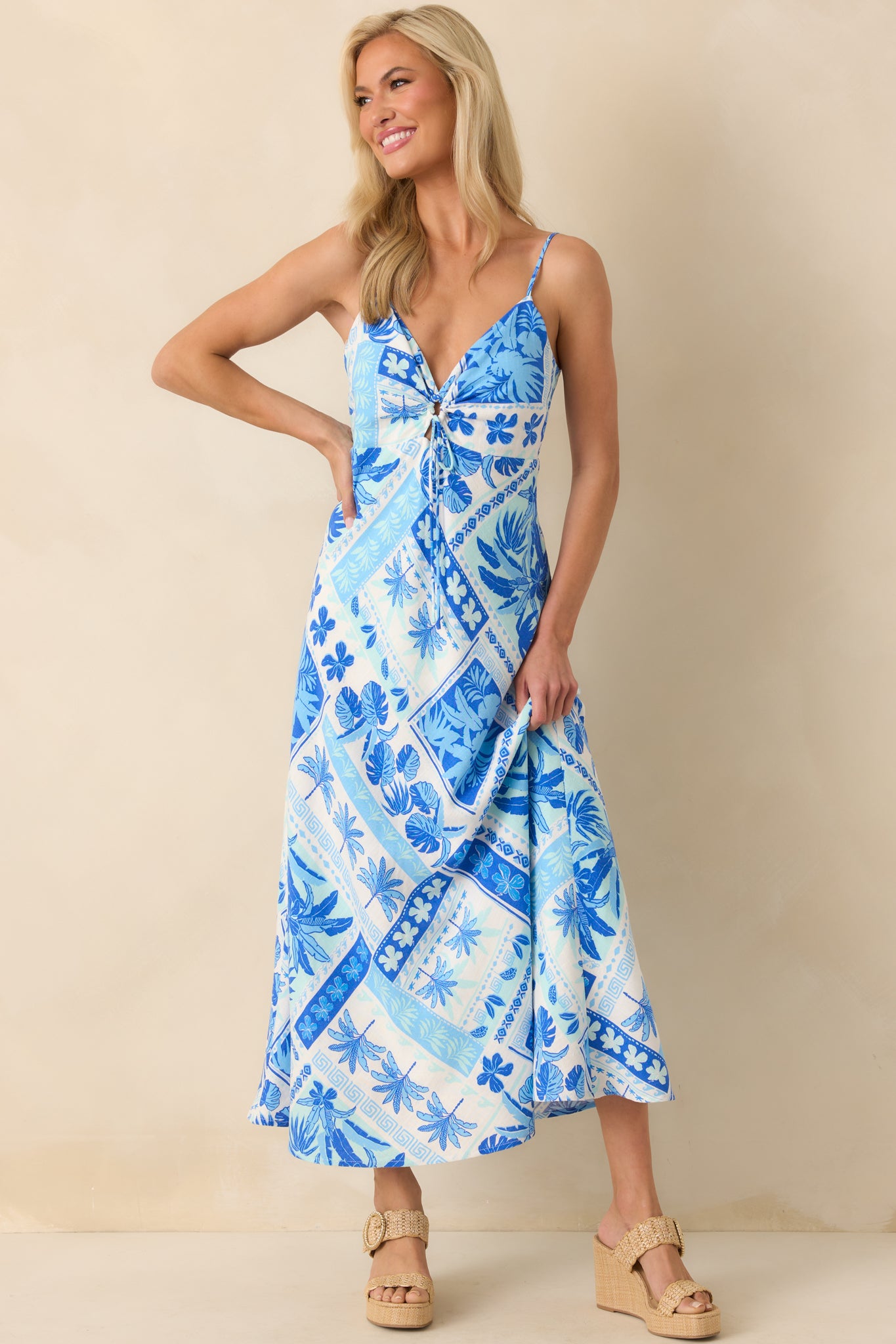 Full body view of the maxi dress showcasing the multi-tone blue tropical patchwork print and deep v-neckline with a self-tie keyhole cutout.