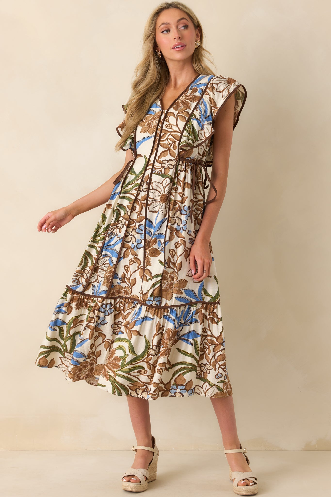 A full body image showcasing the paneled design and adjustable self-tie waist bows on both sides of the floral dress.
