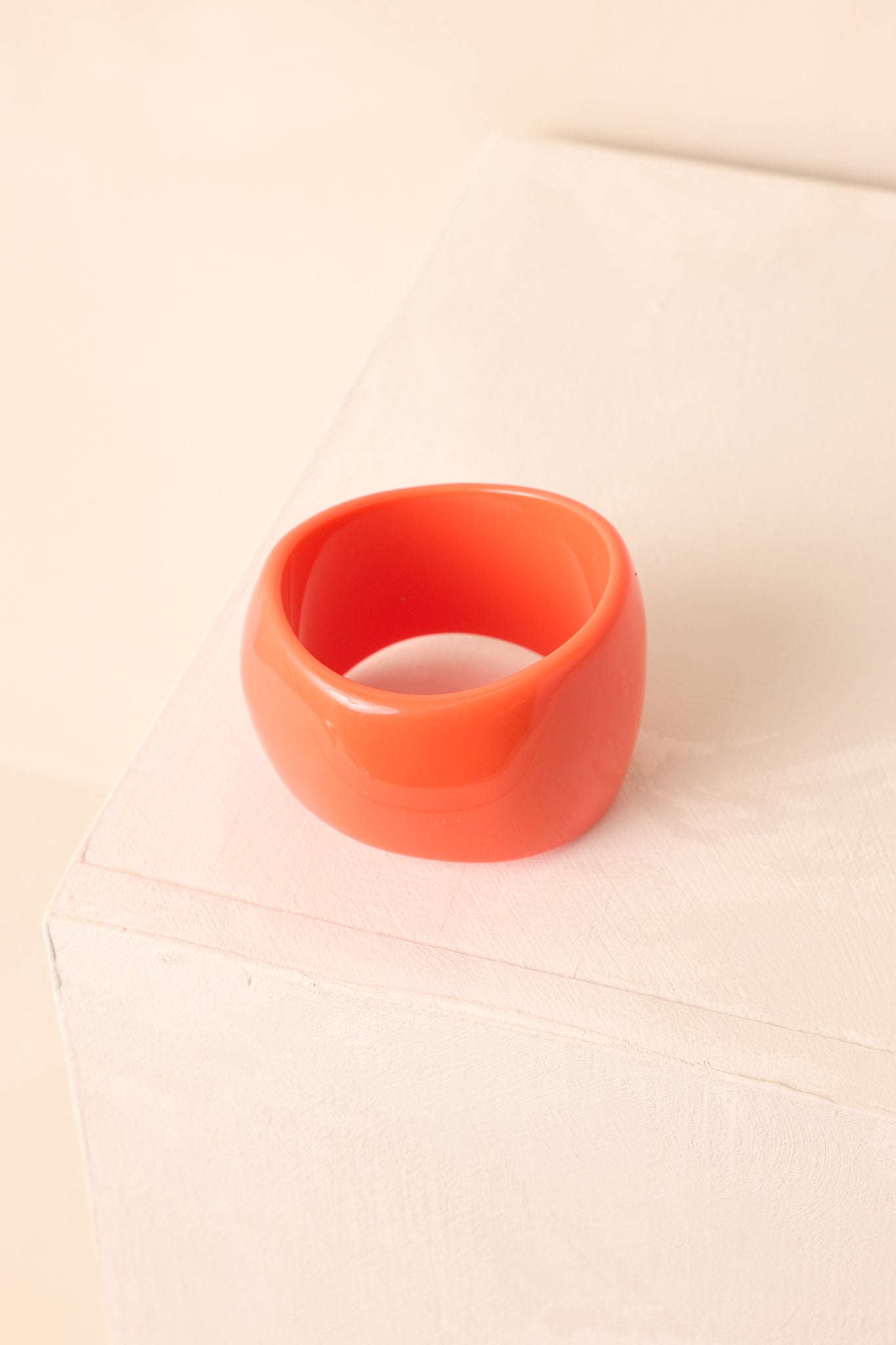 Bold statement orange bracelet highlighting its glossy surface and curved silhouette.