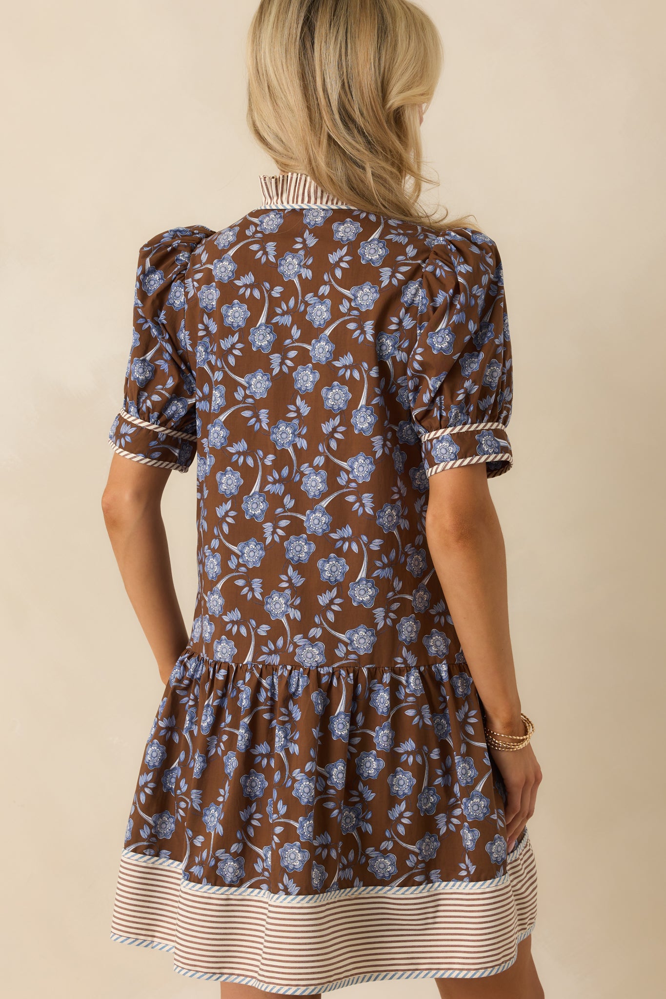 Rear view of the brown mini dress with tiered skirt and puff sleeves finished in floral print.