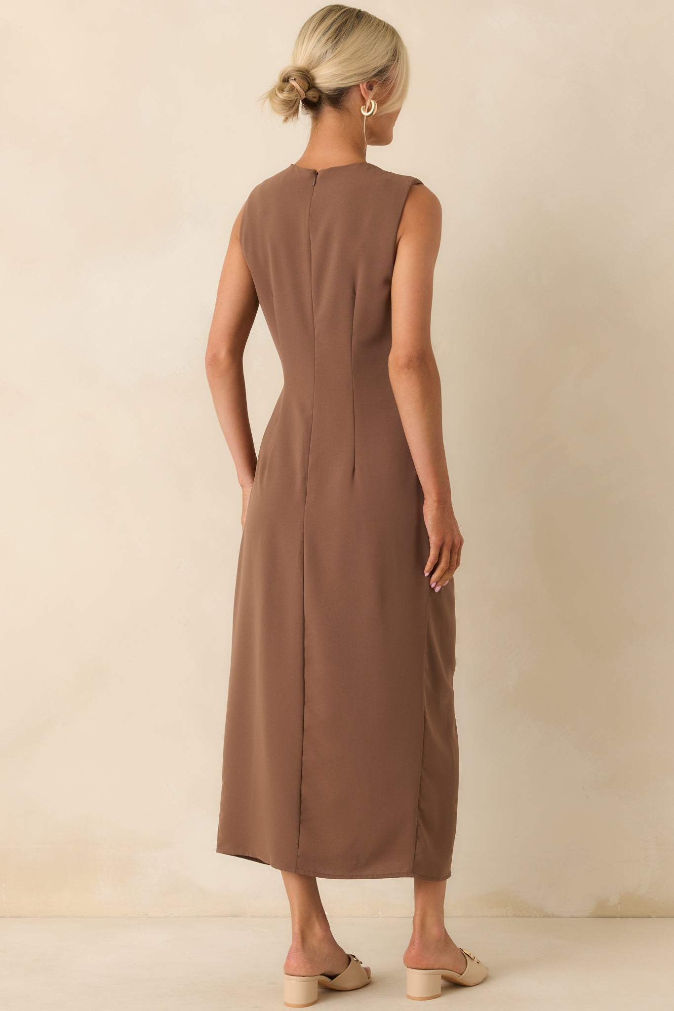 A view from behind of the light brown dress, displaying the sleeveless cut, round neckline, and smooth back design.