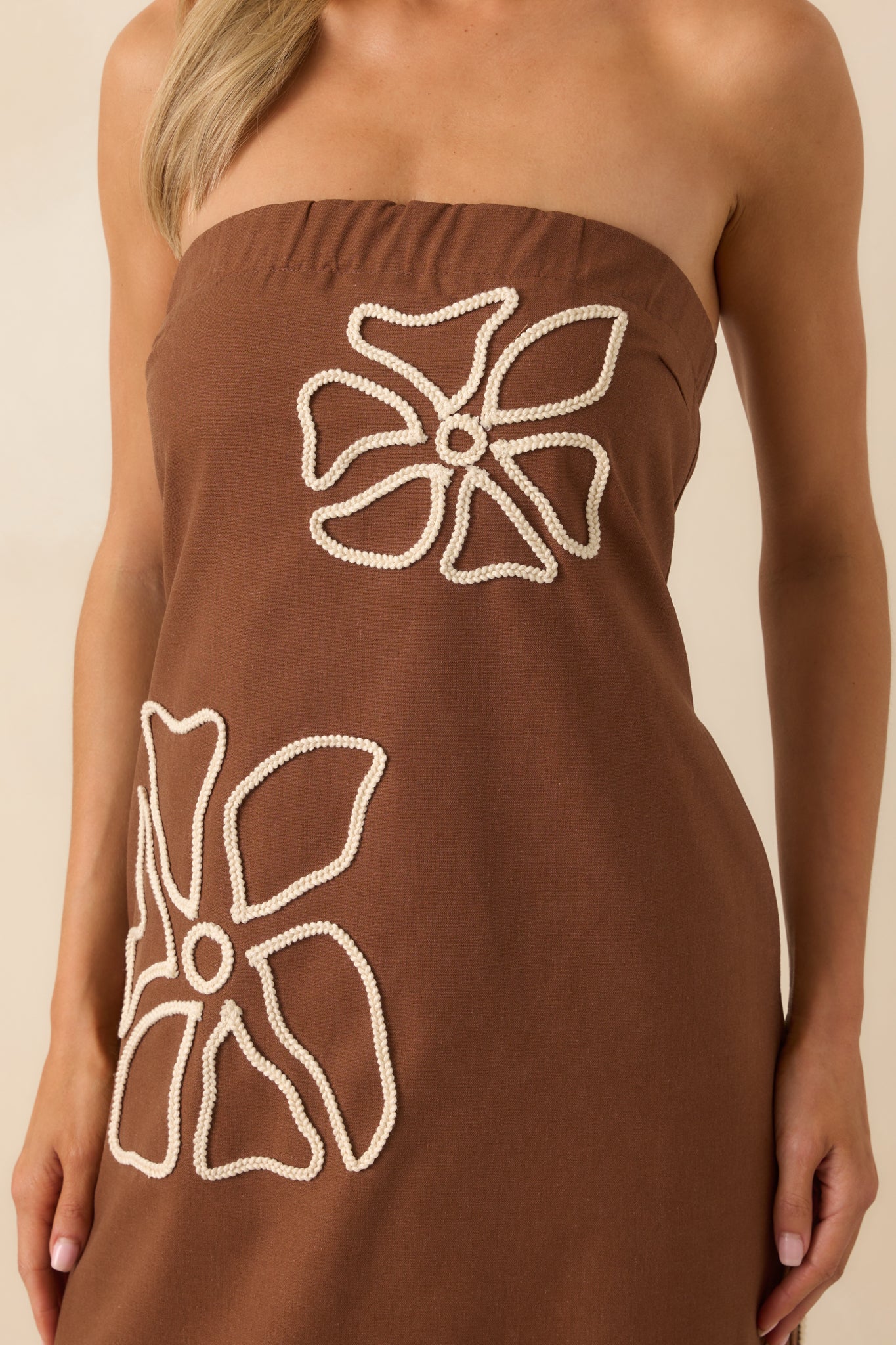 Close-up detail of the ivory braided floral embroidery on the brown fabric, showing the raised texture and stitching.