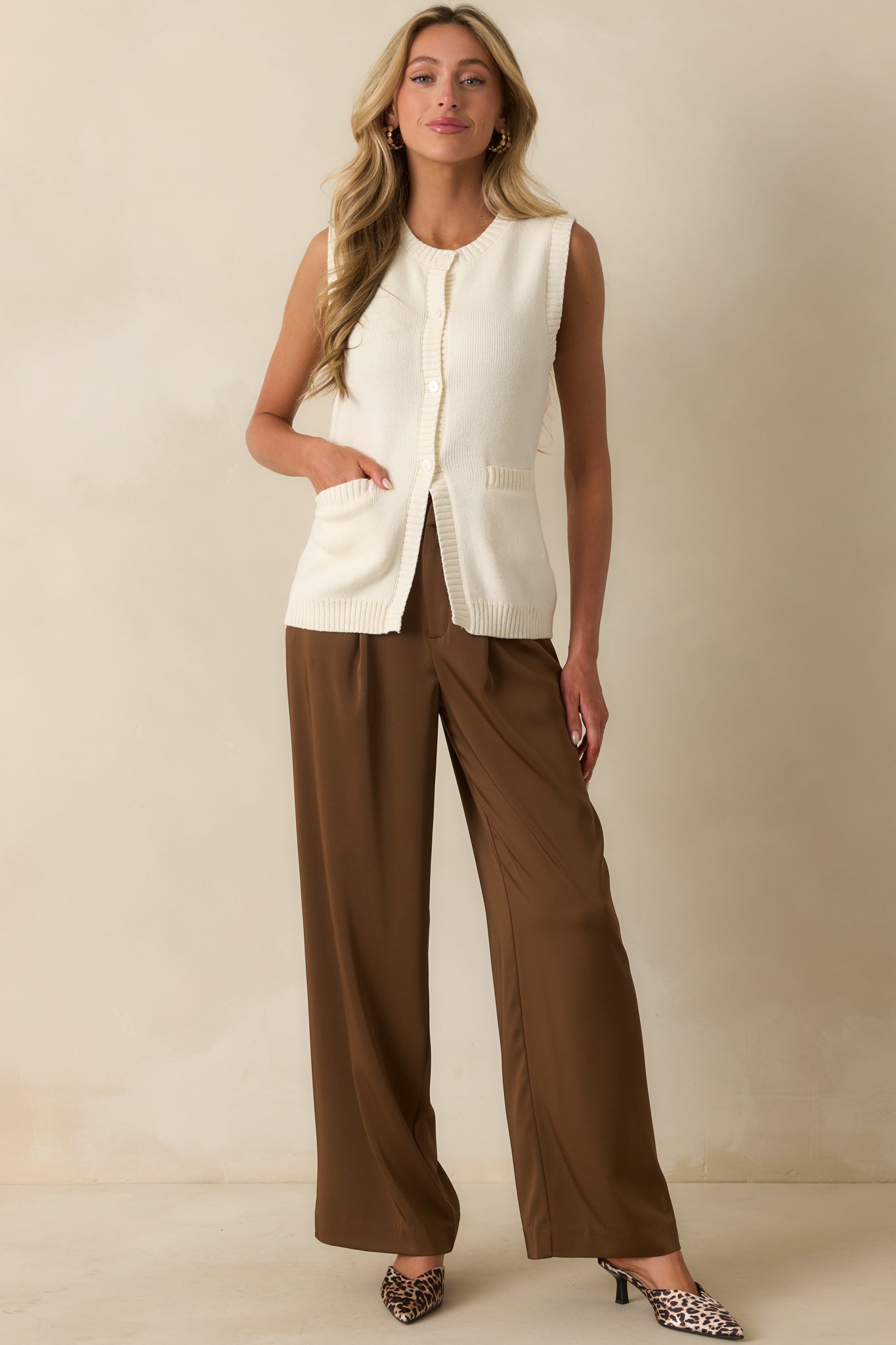 Brown high-rise trousers with front pleats and a wide-leg silhouette.