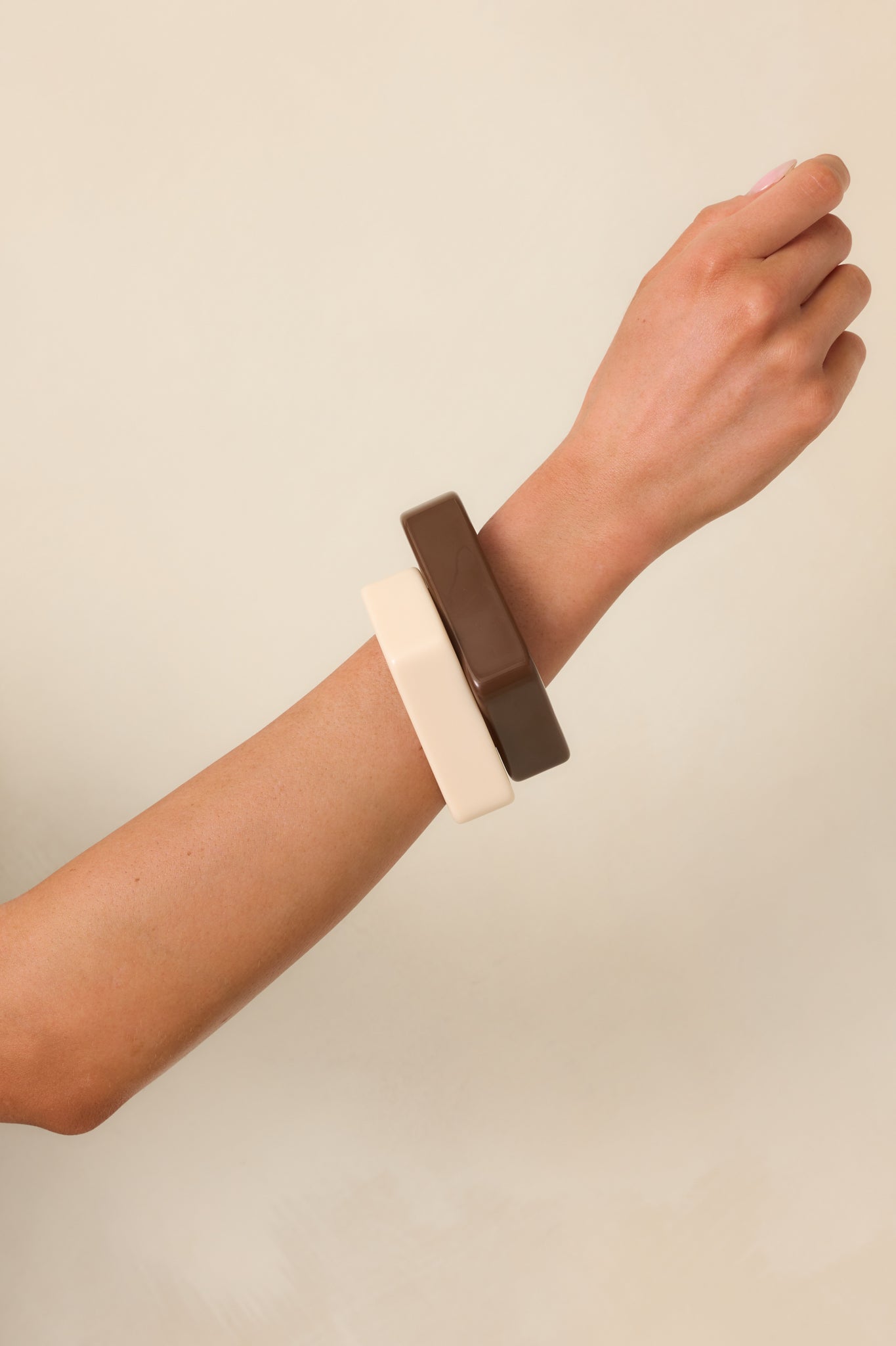 Cropped image focused on the edge detail of the cream and brown bangles, emphasizing their sculptural form.