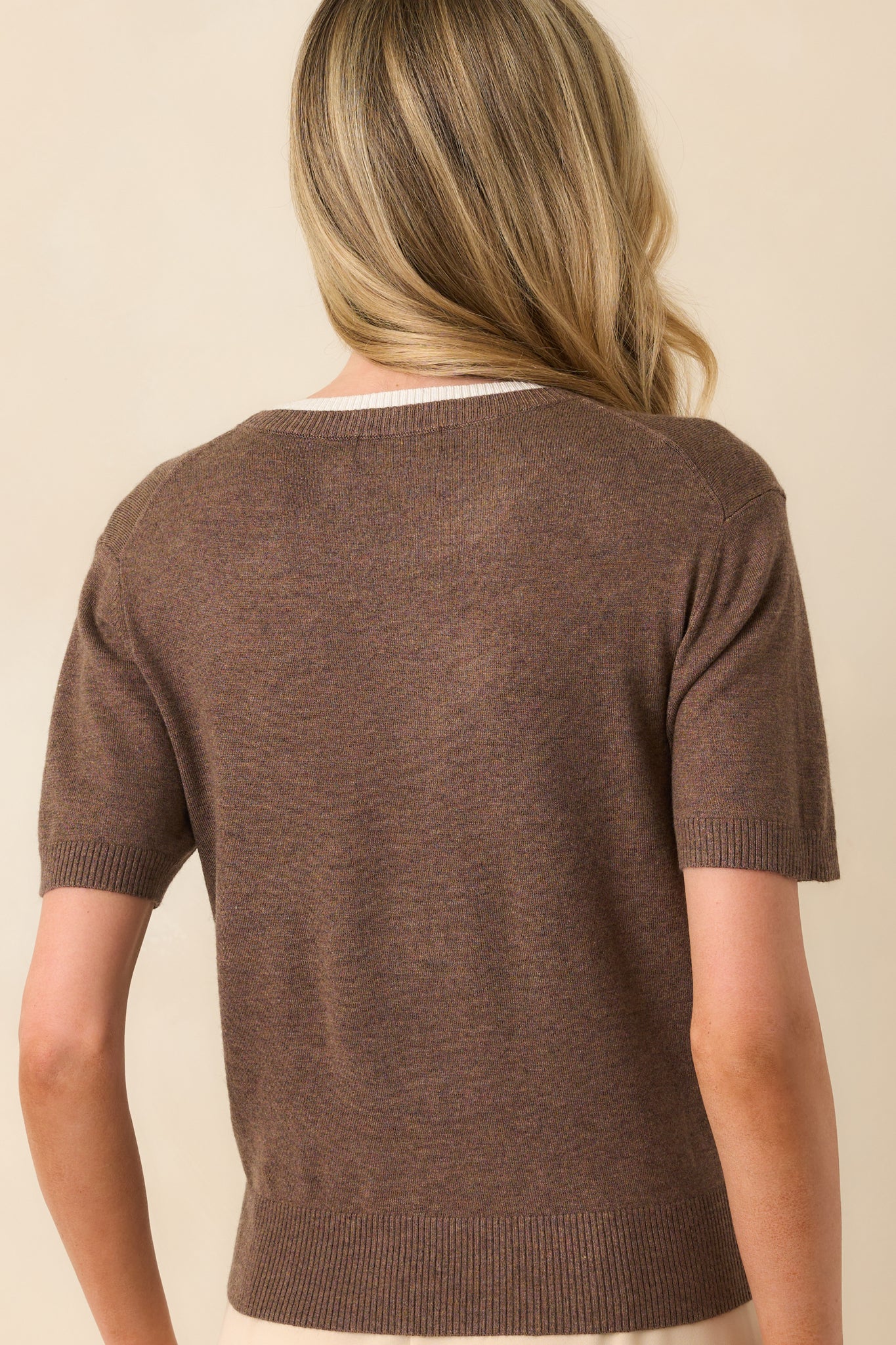 A back view of the top featuring the ribbed hem and cuffs, and the soft knit fabric extending throughout.