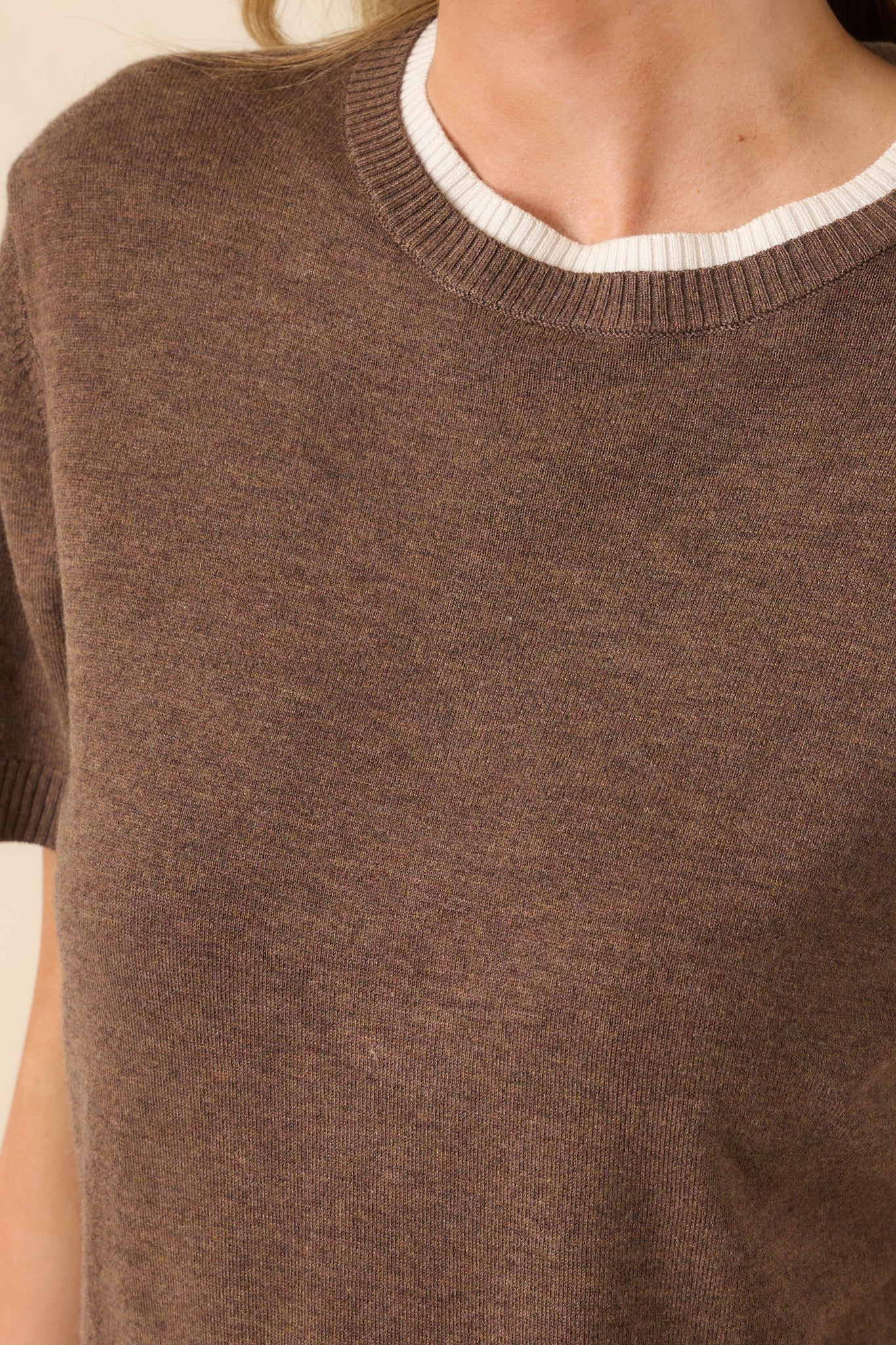 A close-up detail of the neckline showing the ribbed texture and beige underlayer beneath the round collar.