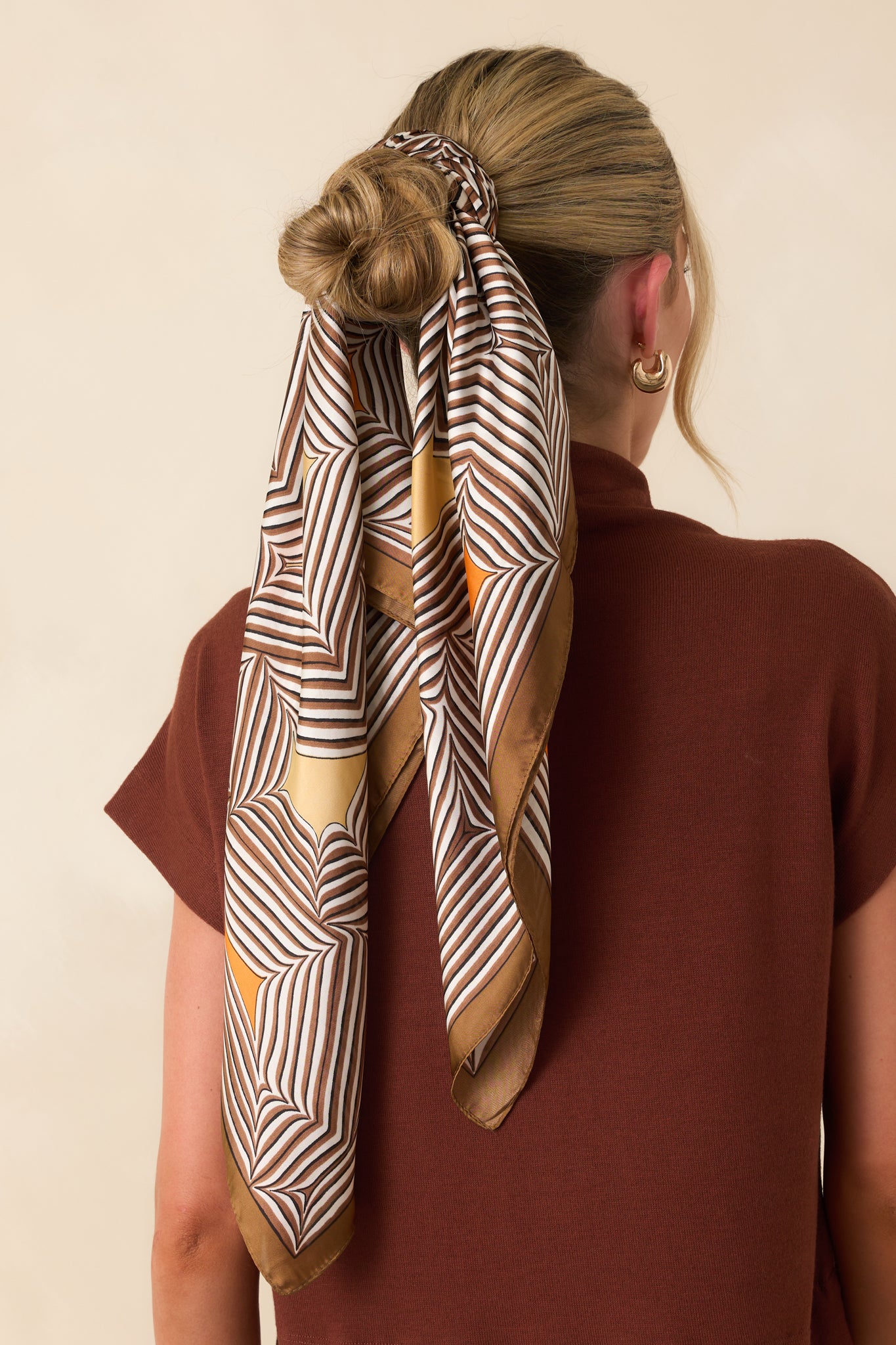A view from behind showing the scarf styled on the head, with the geometric pattern and warm-toned details visible across the back.