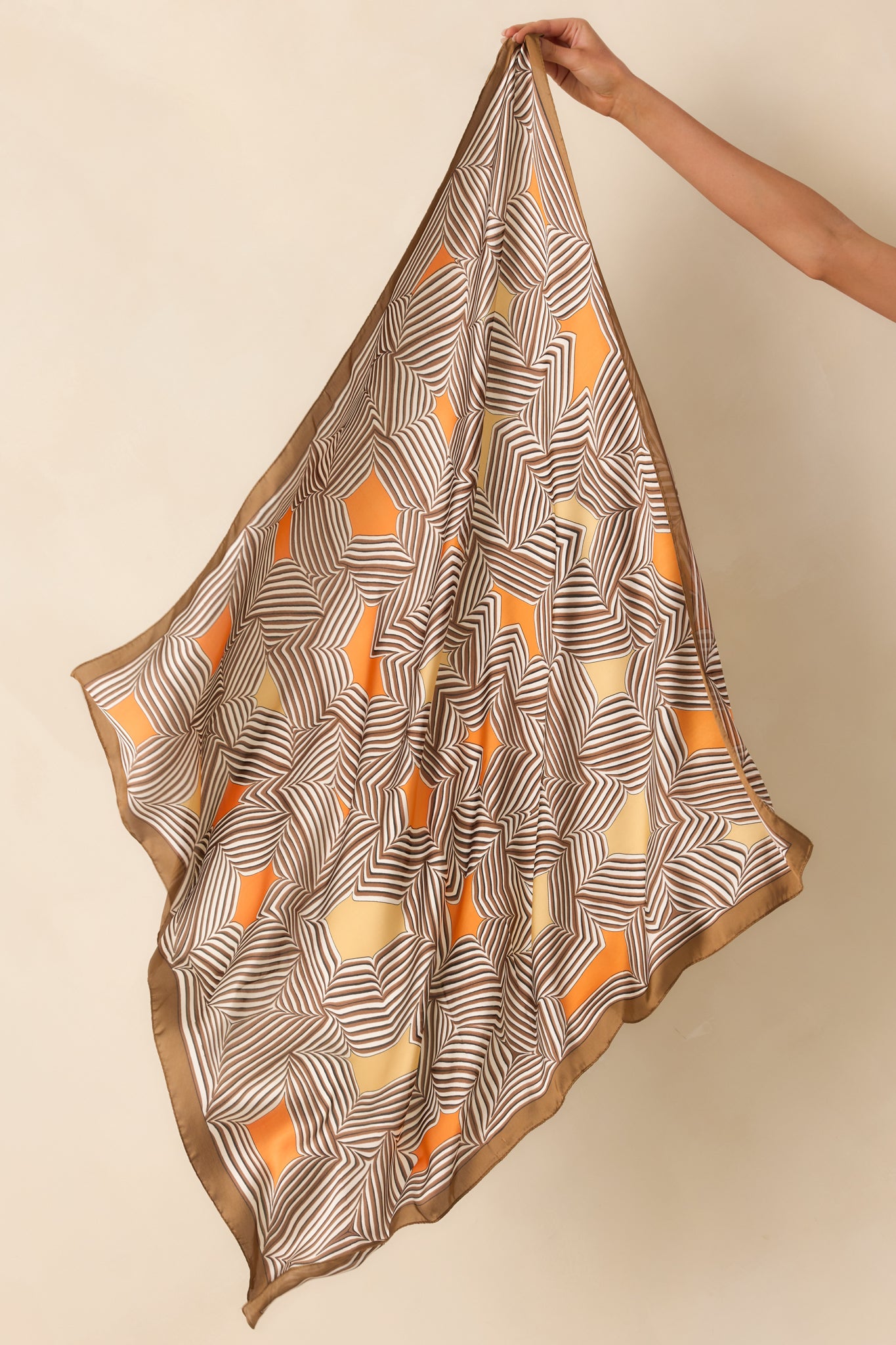 Angled image of the scarf laid out to highlight its large square shape and the smooth, glossy satin texture.