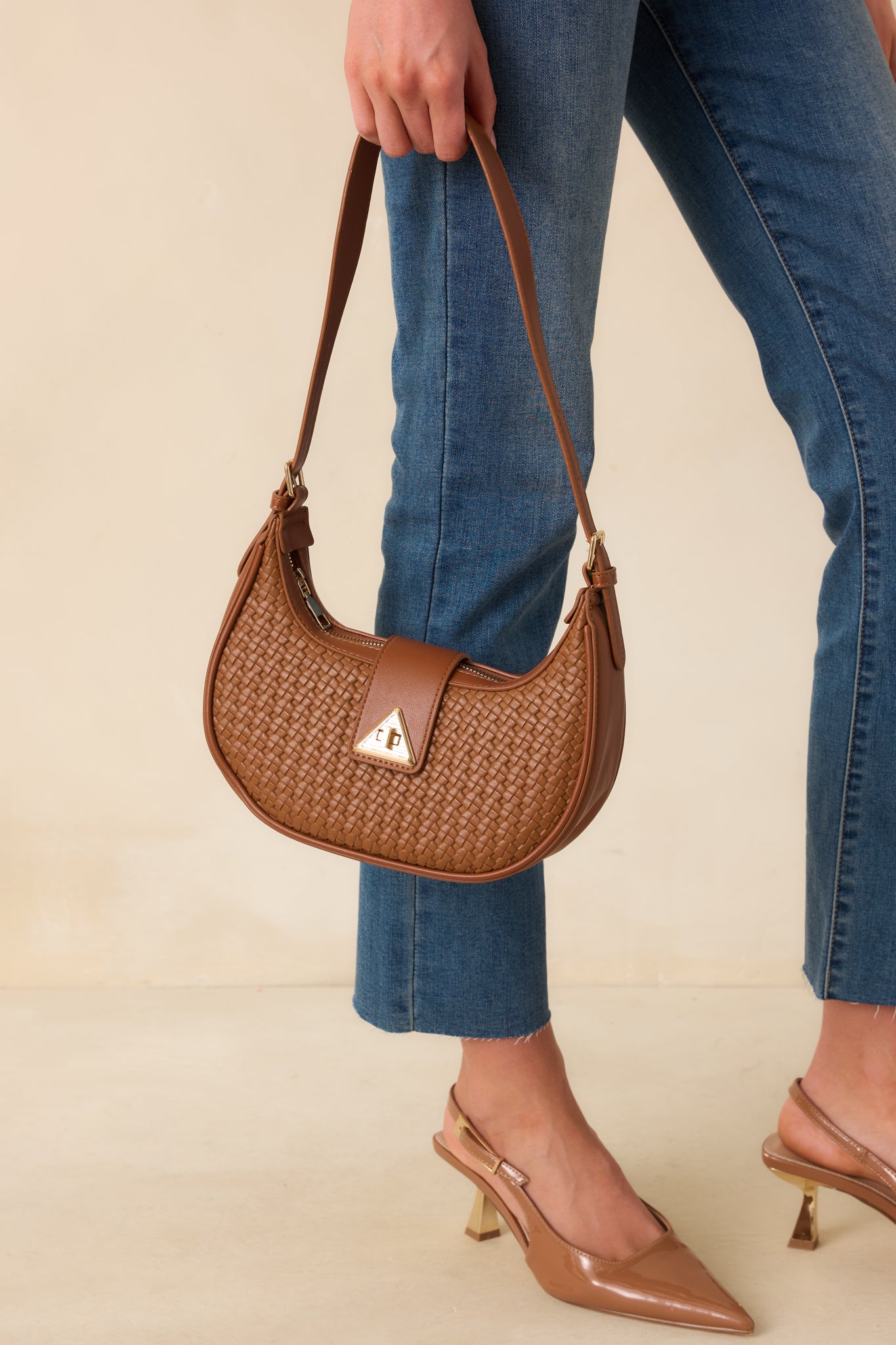 Cropped shot capturing the texture of the woven faux leather and the curve of the half-moon silhouette.