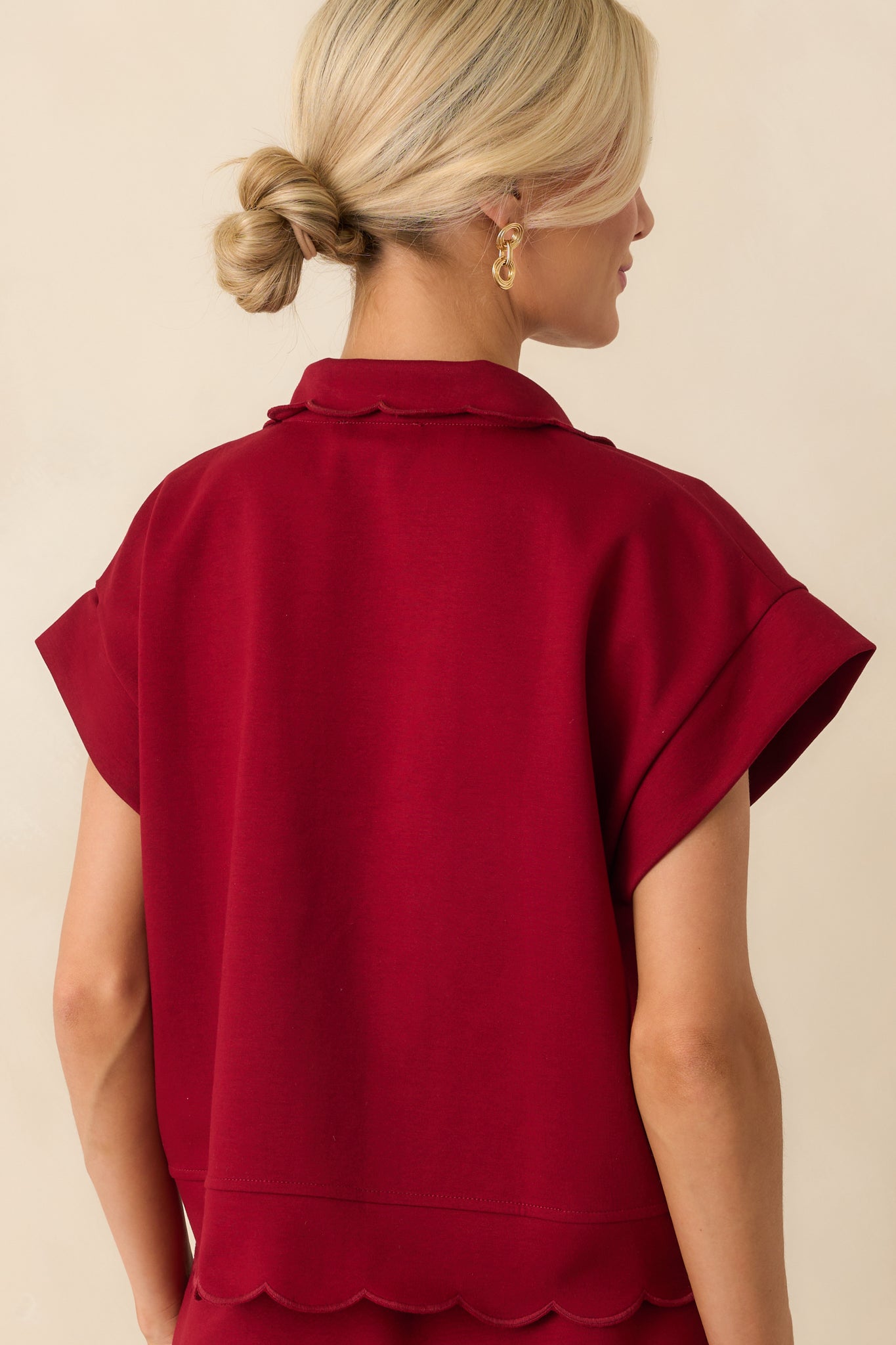 A back view of the burgundy pullover featuring the relaxed fit and scalloped hem detail along the back hemline.