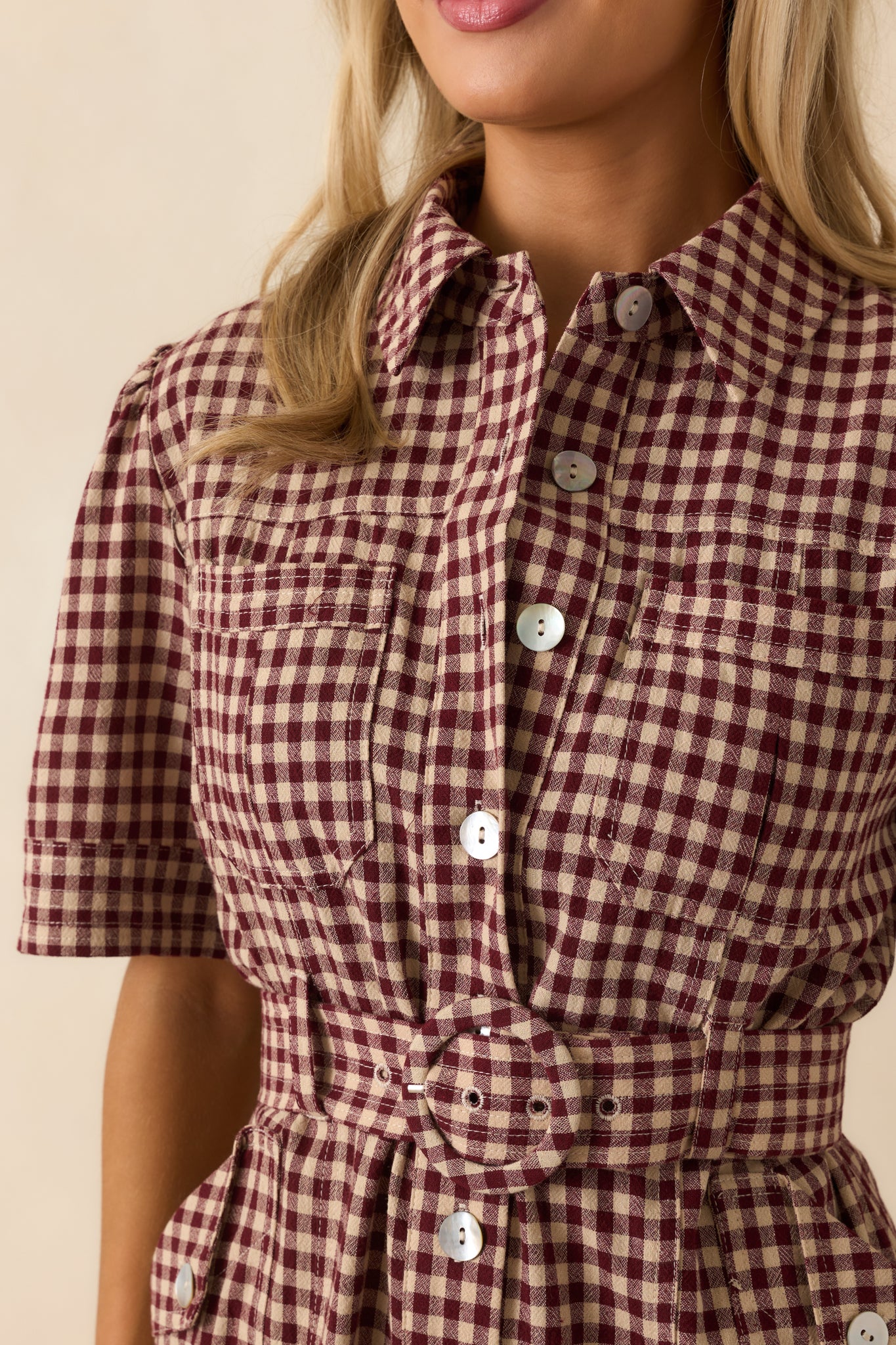 Detail shot of the gingham fabric texture and stitching around the button closure.