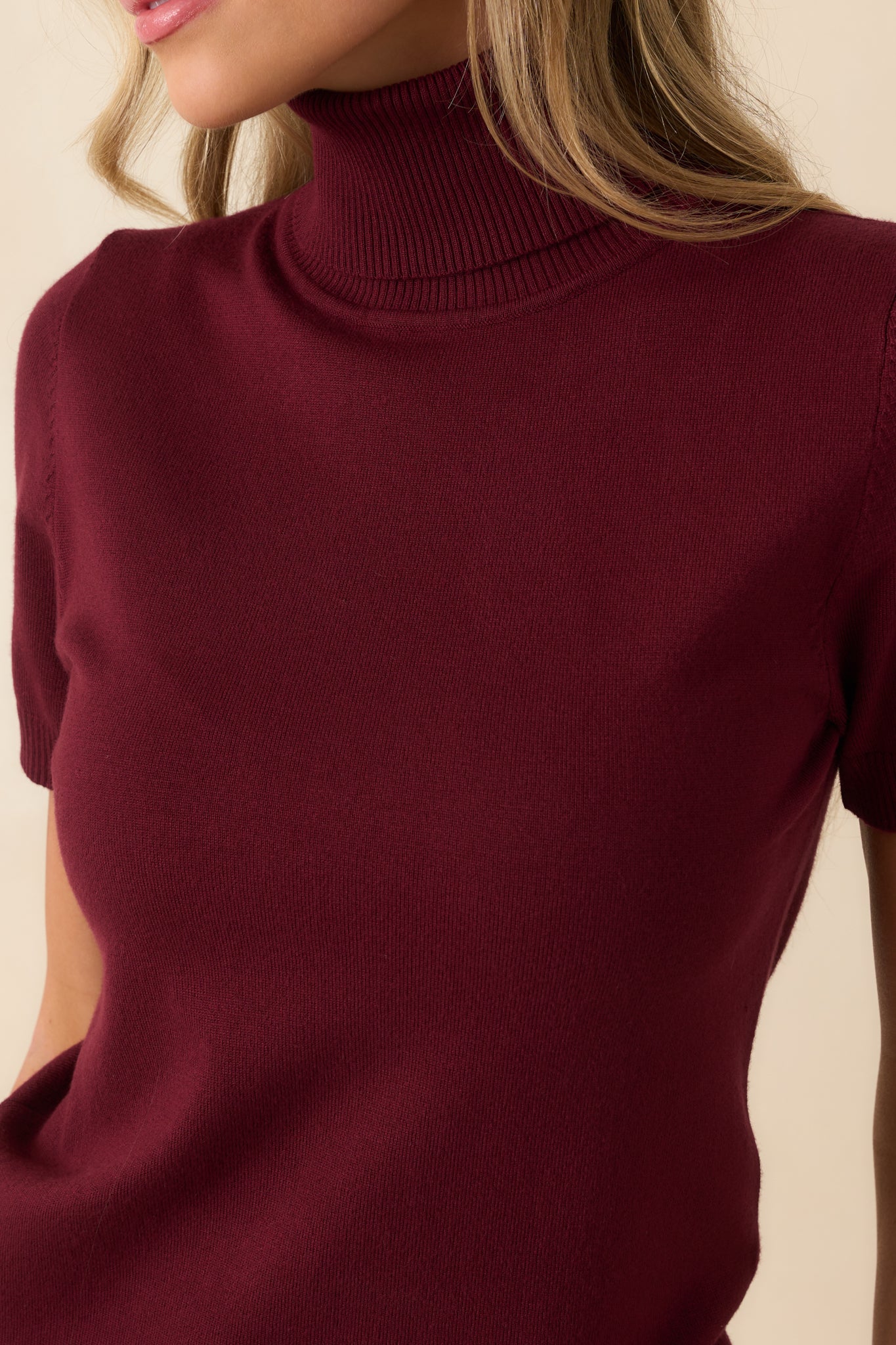 Detail of short sleeves with ribbed hems on the wine red sweater.