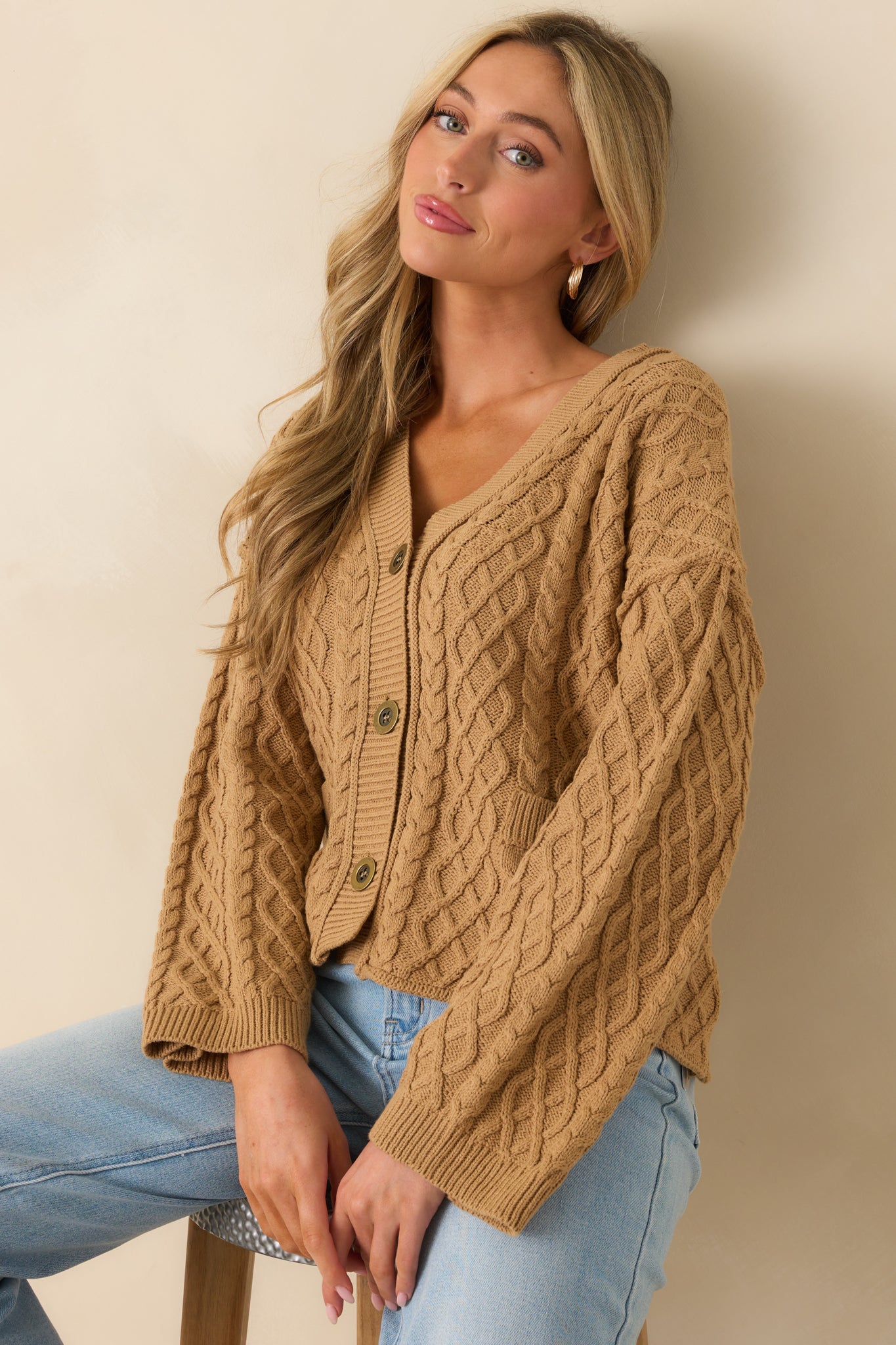 Cropped photo showing the ribbed hem and lower front portion of the camel cardigan.