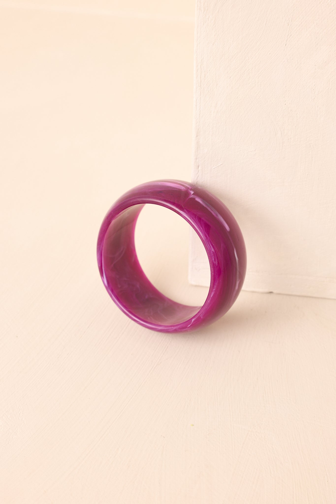 Chunky purple marbled bangle bracelet displayed on a beige surface.